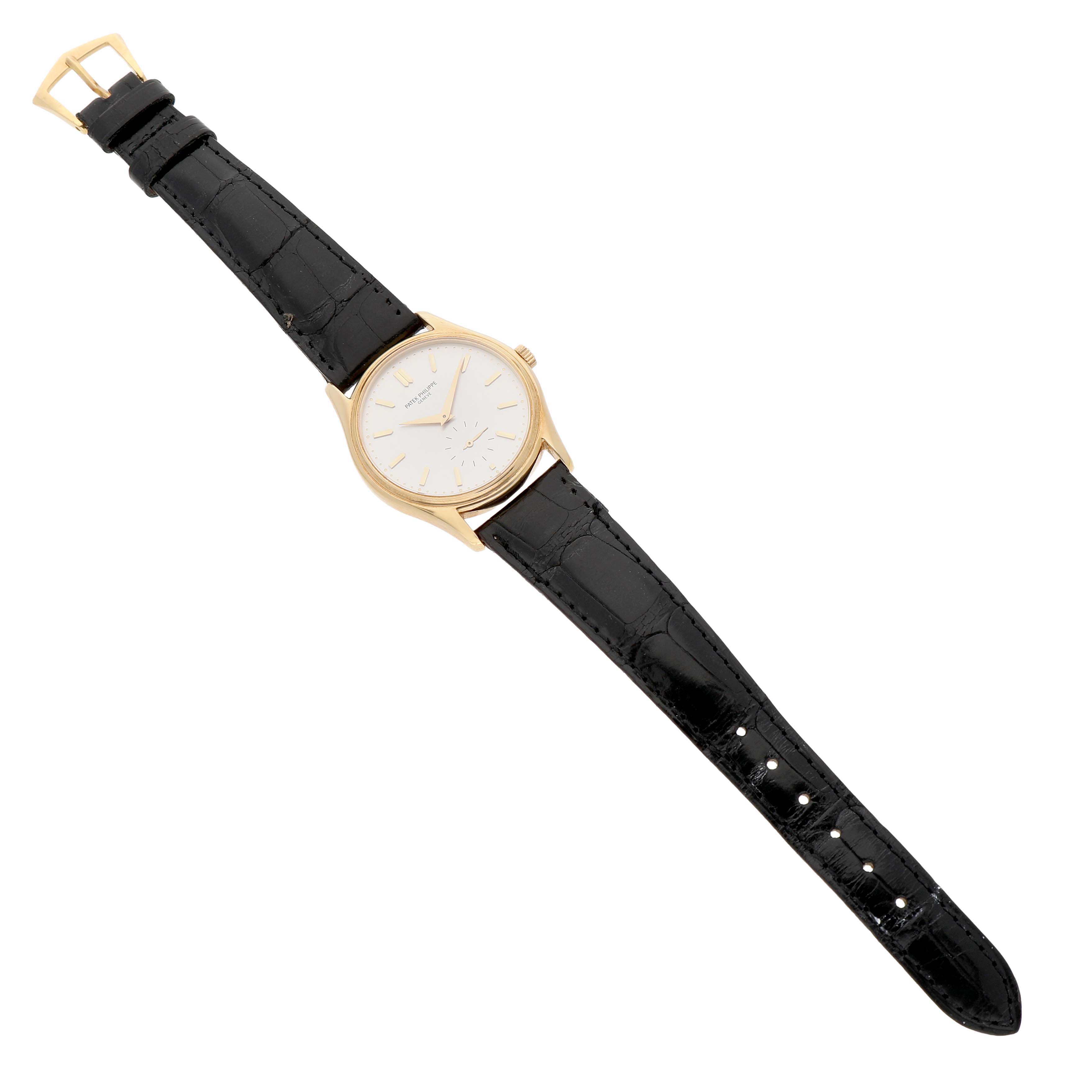 The Patek Philippe Calatrava 5023 5023J Men's Yellow Gold Silver Dial watch is shown from a top view, displaying its face, black strap, and gold buckle.