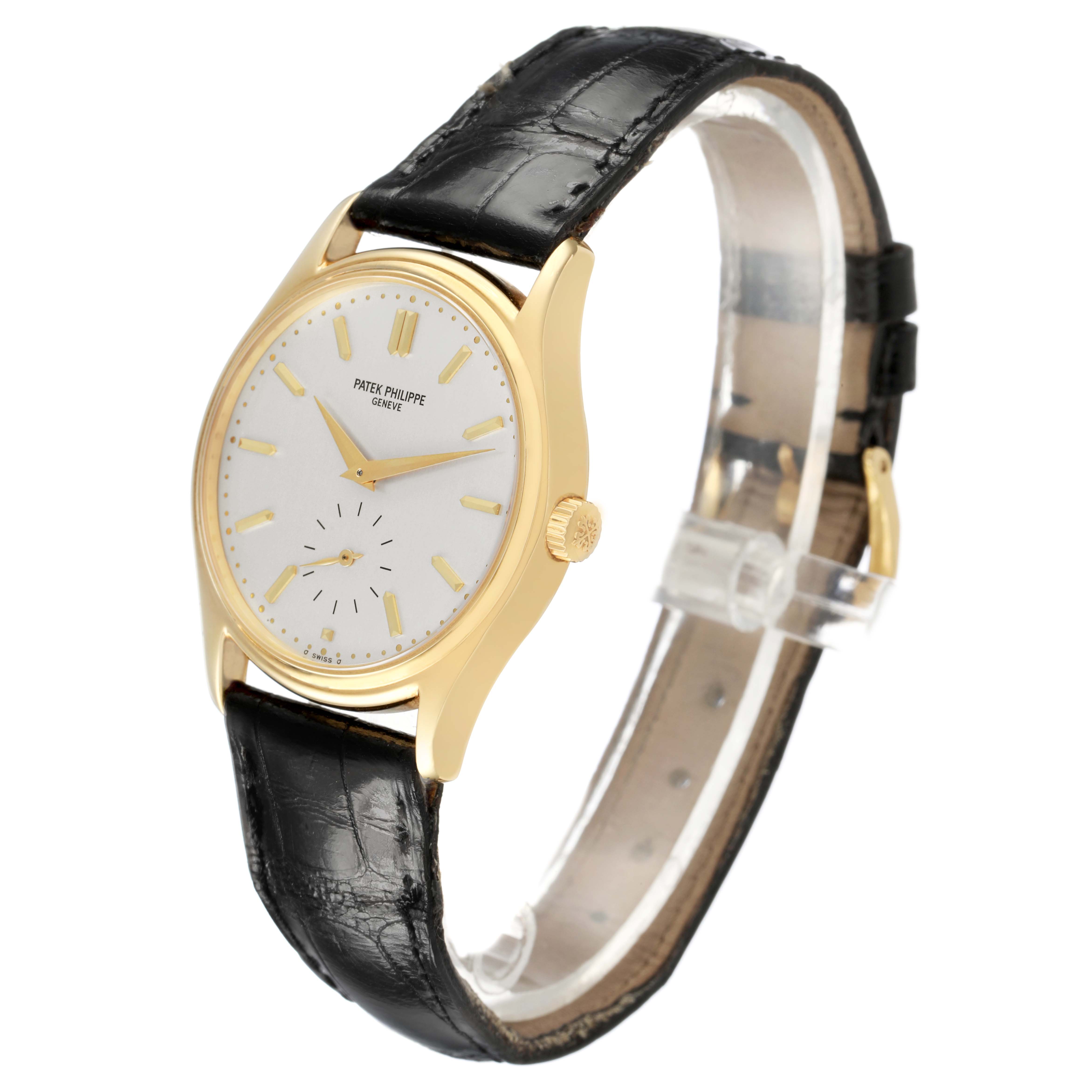The Patek Philippe Calatrava 5023 5023J Men's Yellow Gold Silver Dial watch is shown at a three-quarter angle, displaying its face, case, and black leather strap.