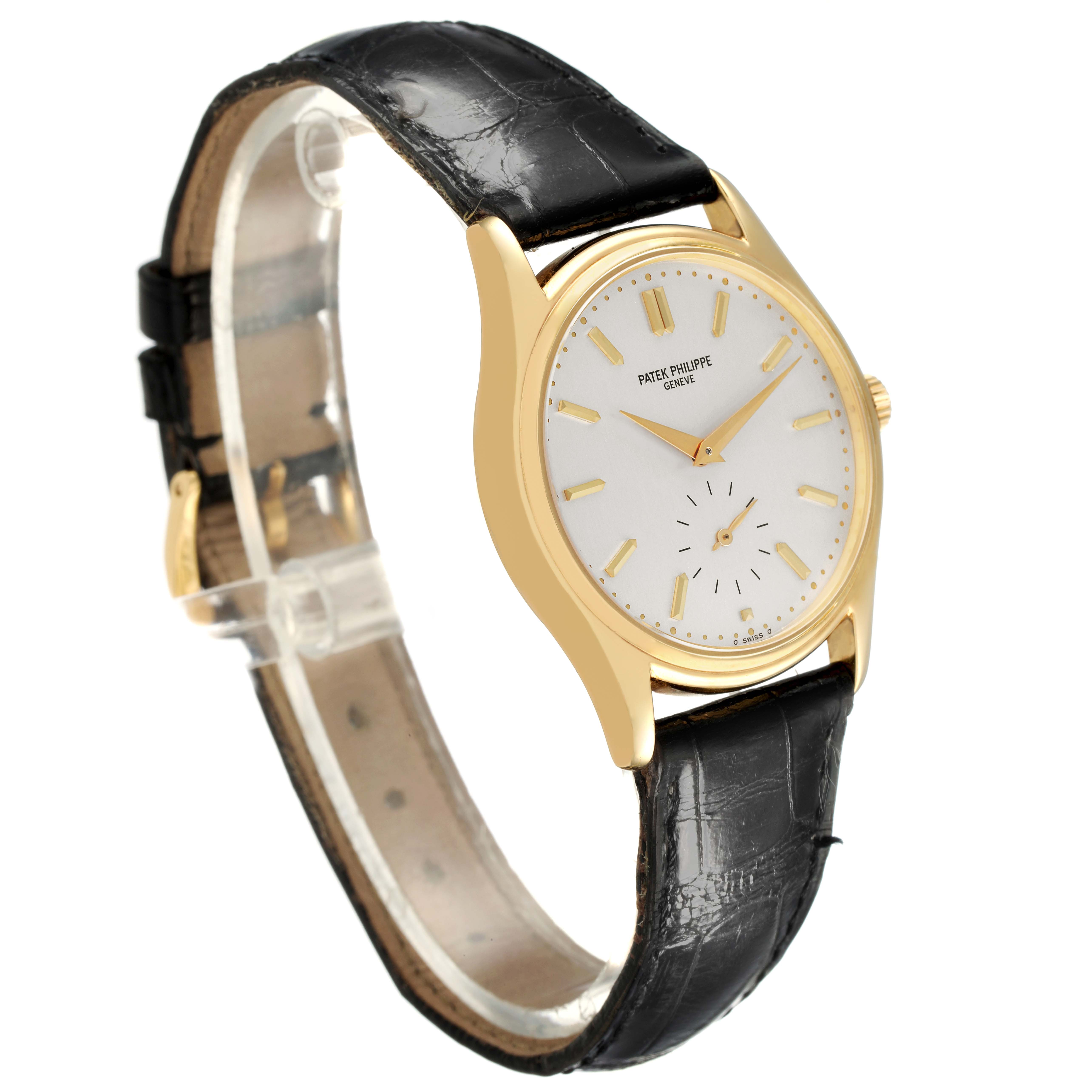 The Patek Philippe Calatrava 5023 5023J Men's Yellow Gold Silver Dial watch is shown at an angled side view, highlighting the dial, case, crown, and leather strap.