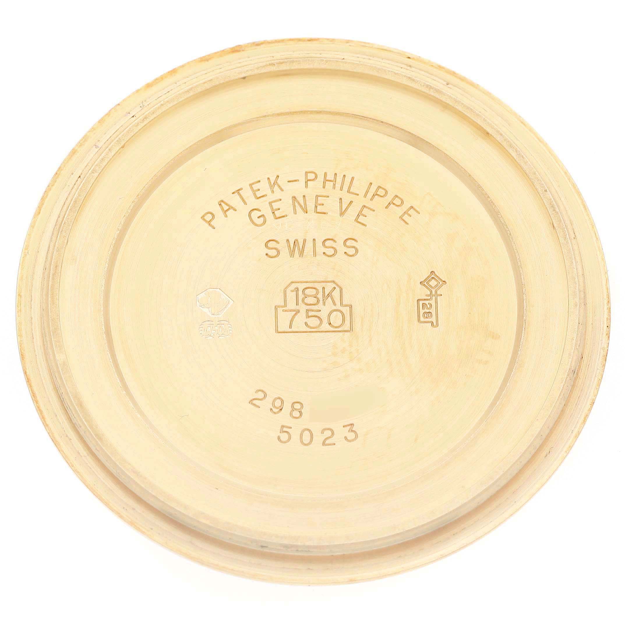 The image shows the inside of the case back from a Patek Philippe Calatrava 5023 5023J Men's Yellow Gold Silver Dial watch, highlighting engravings and material specifications.