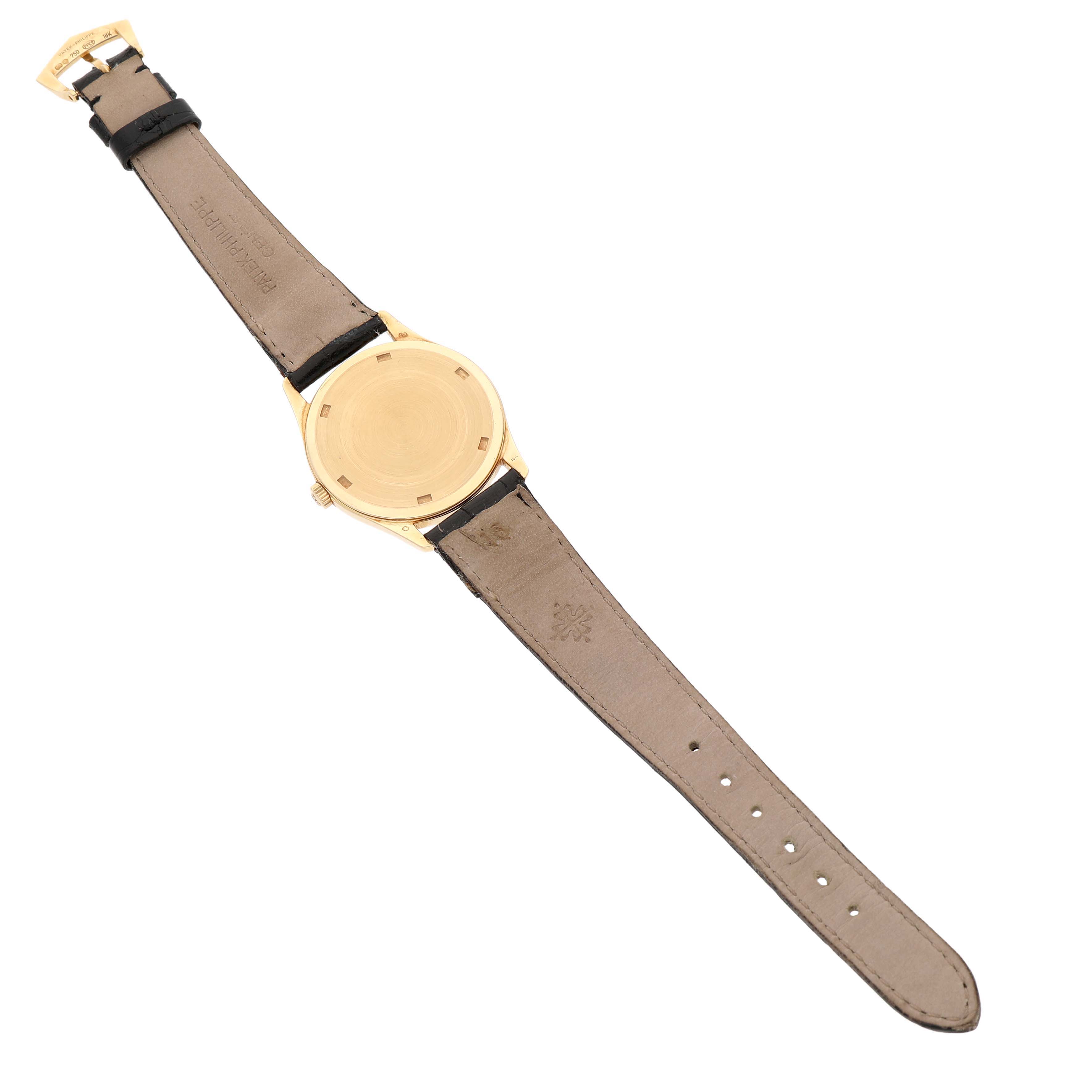 The image shows a Patek Philippe Calatrava 5023 5023J Men's Yellow Gold Silver Dial watch from the back, displaying its leather strap and gold case back.