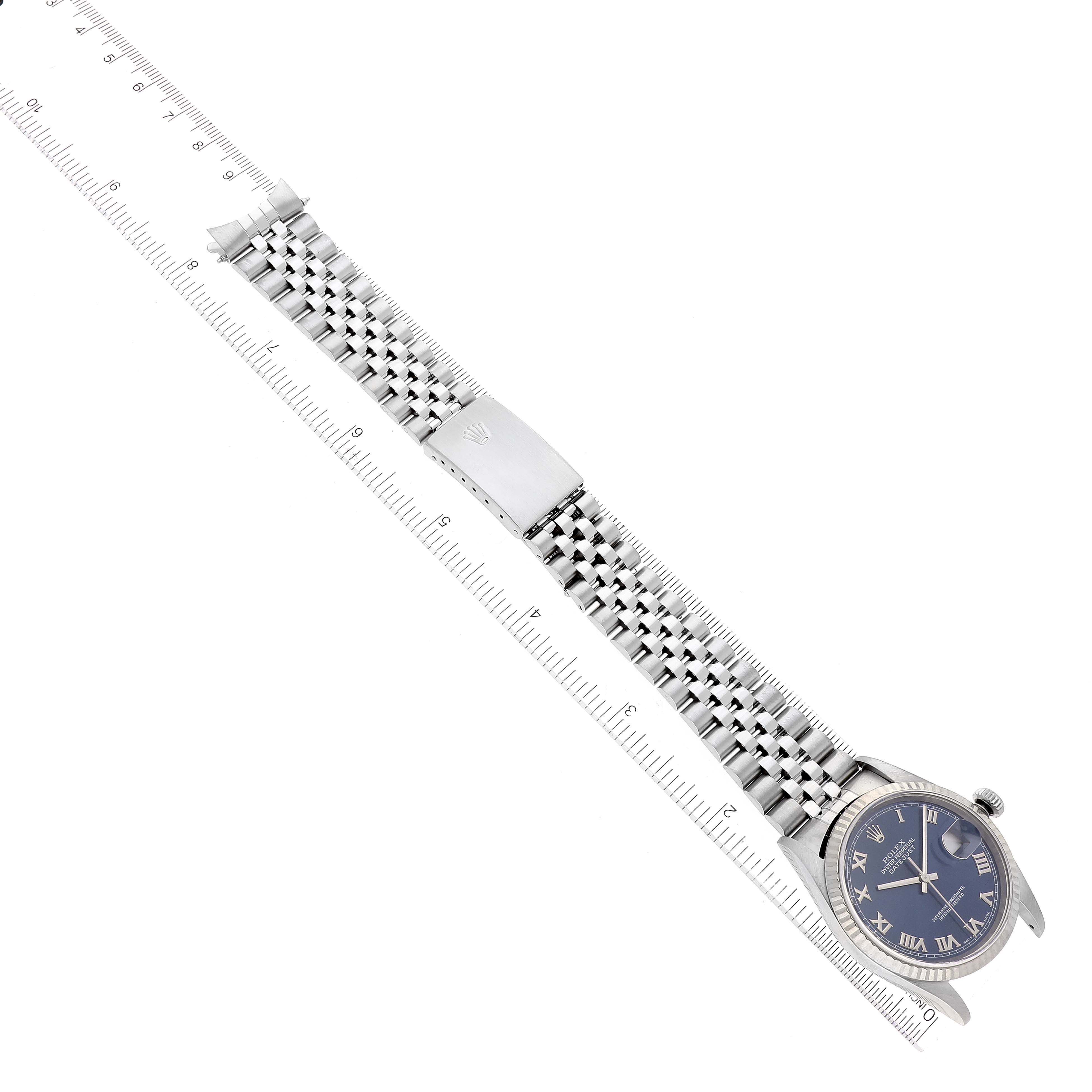 The image shows a Rolex Datejust 16234 Men's Stainless Steel Blue Dial 16234 Men's Stainless Steel Blue Dial watch from an aerial view, emphasizing its face, bracelet, and clasp alongside a measuring ruler.