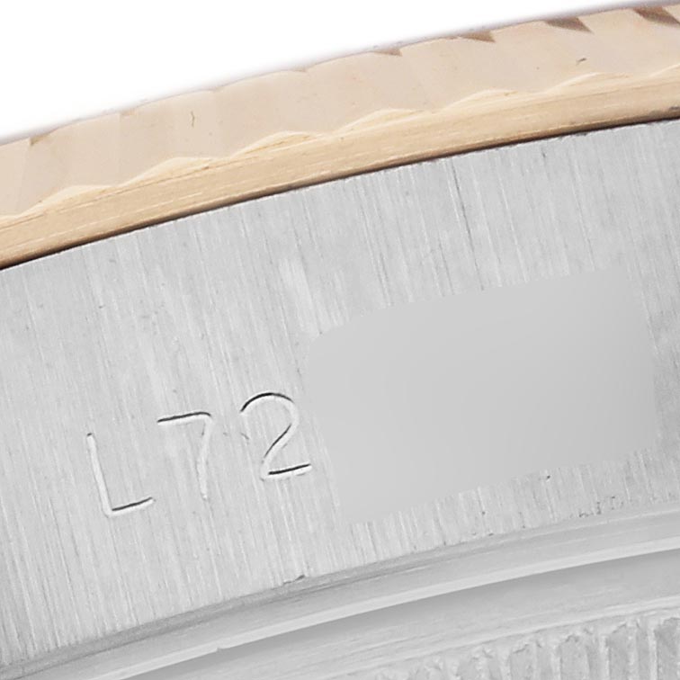 The image shows a close-up of the Rolex Datejust 69173 Women's Steel and Gold (two tone) Champagne Dial 69173 Women's Steel and Gold (two tone) Champagne Dial's fluted bezel and part of the engraved serial number.