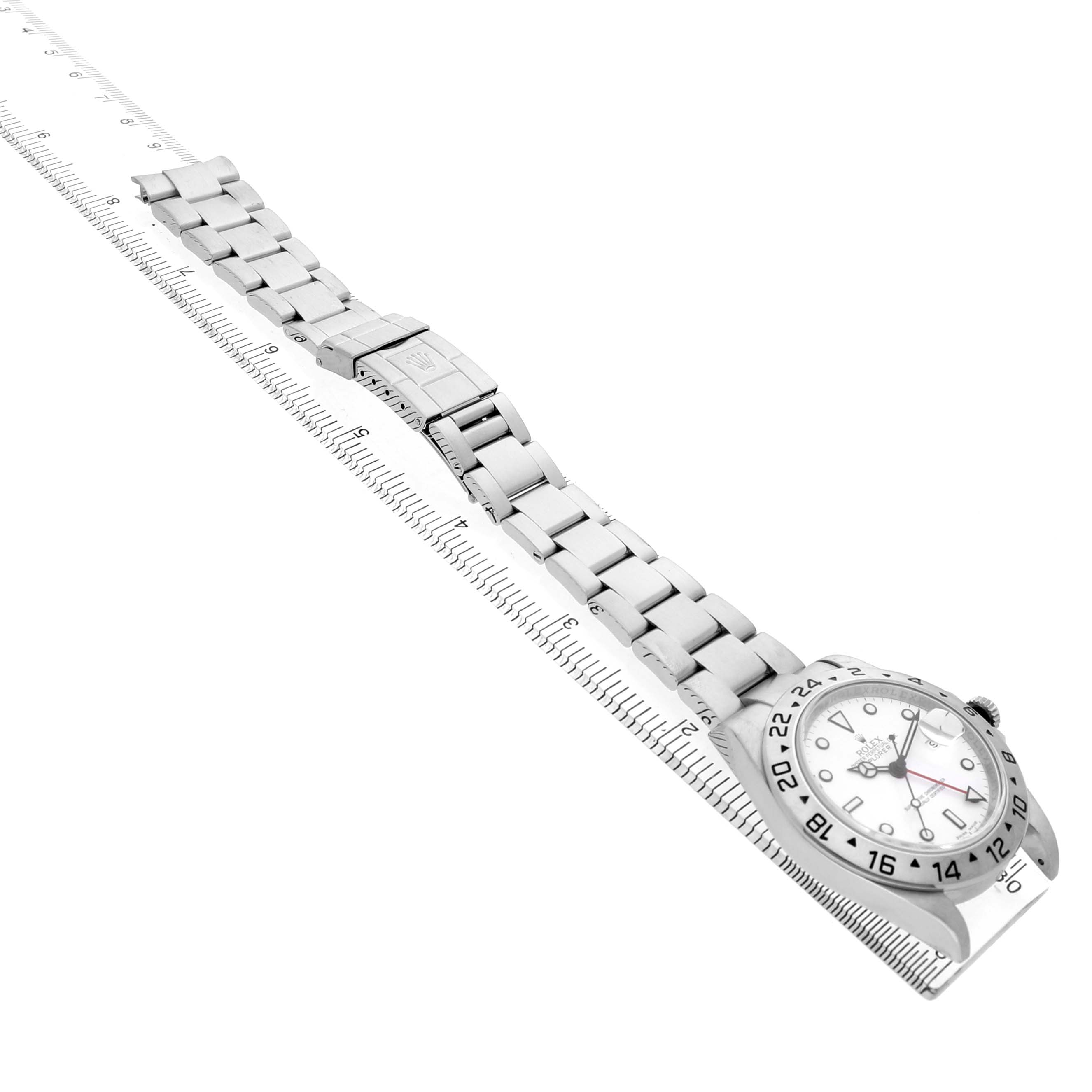 The Rolex Explorer 16570 Men's Stainless Steel White Dial watch is shown at an angled top view, displaying the face, bezel, and full bracelet with a ruler beneath it.