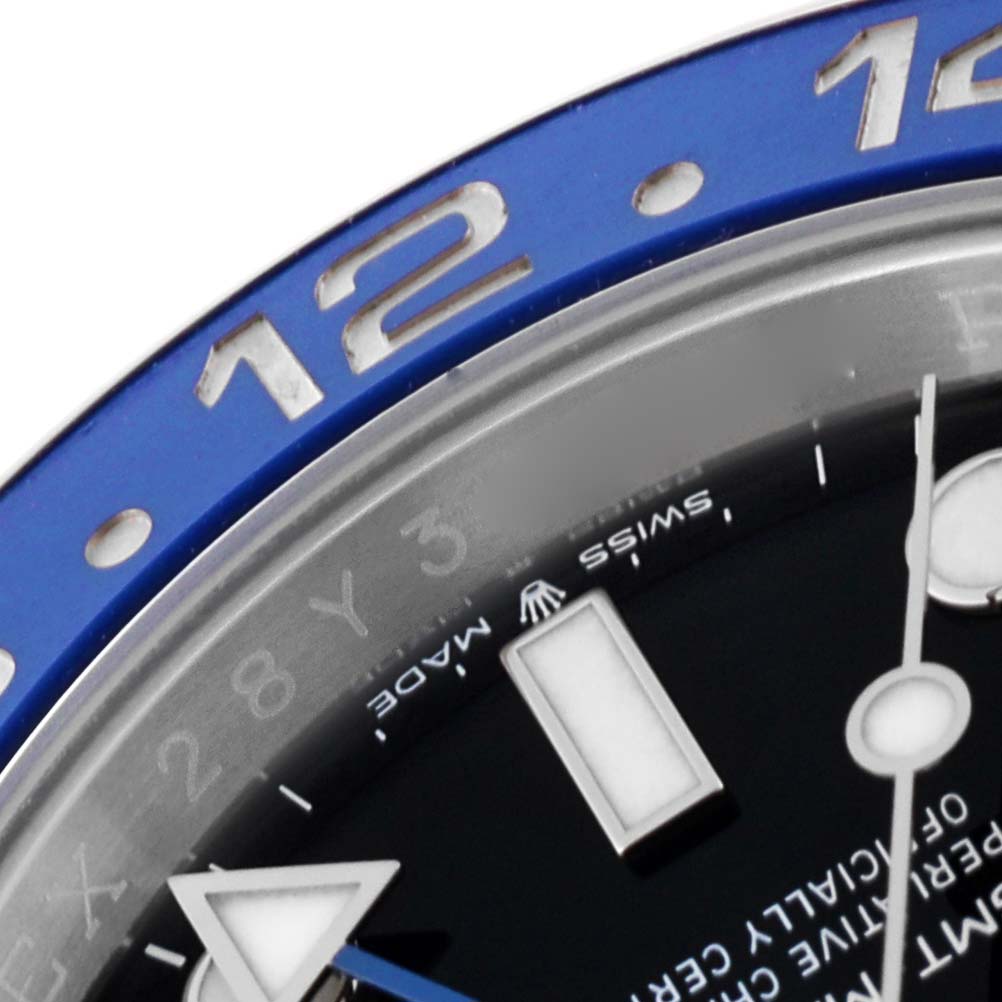 A close-up view of the bezel and part of the dial on the Rolex GMT-Master 126710BLNR Men's Stainless Steel Black Dial 126710BLNR Men's Stainless Steel Black Dial, showing the 12-hour marker, part of the minute and hour hands.