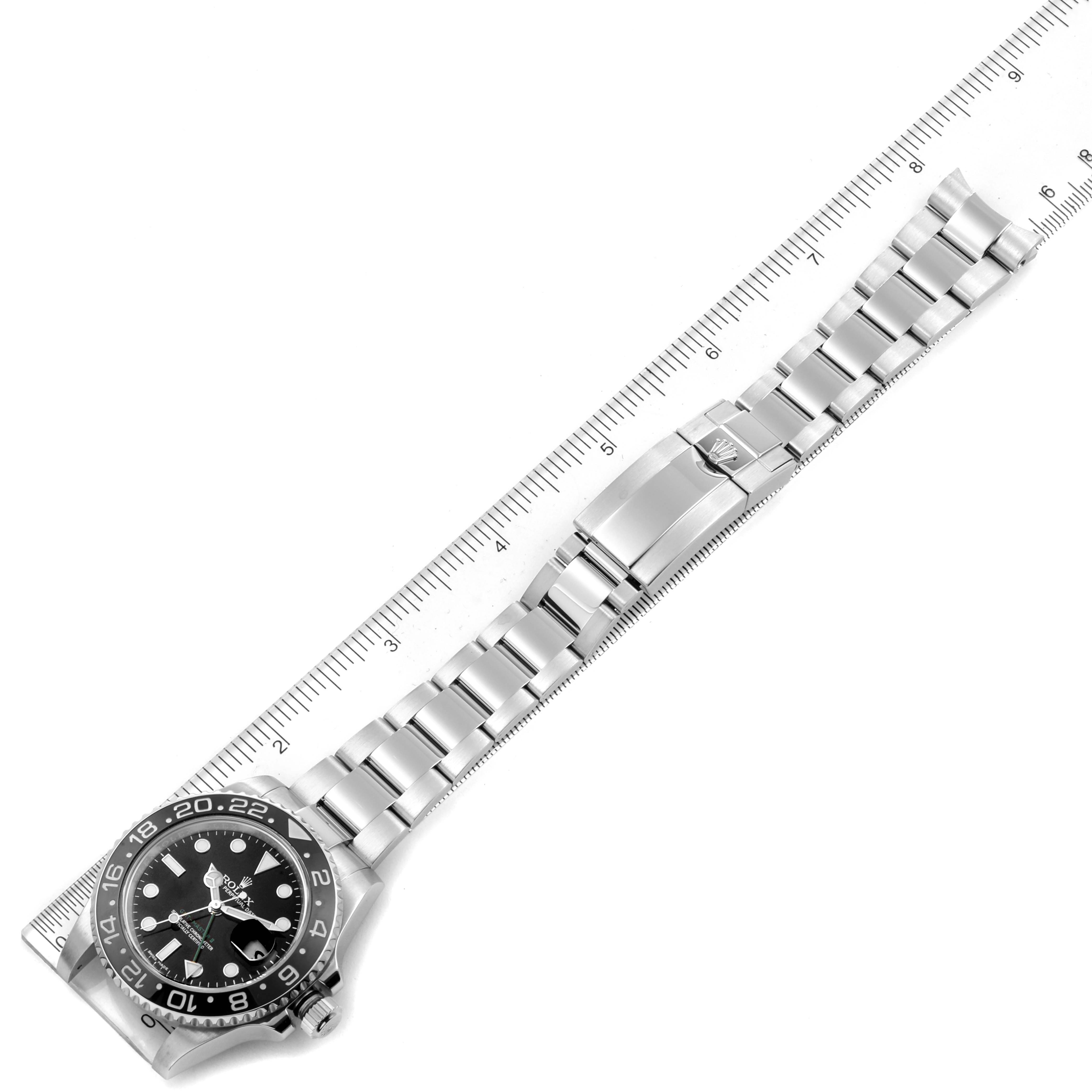 The image shows a top view of a Rolex GMT-Master 116710 Men
s Stainless Steel Black Dial 116710 Men
s Stainless Steel Black Dial watch, displaying its face, bezel, and entire metal bracelet next to a ruler.