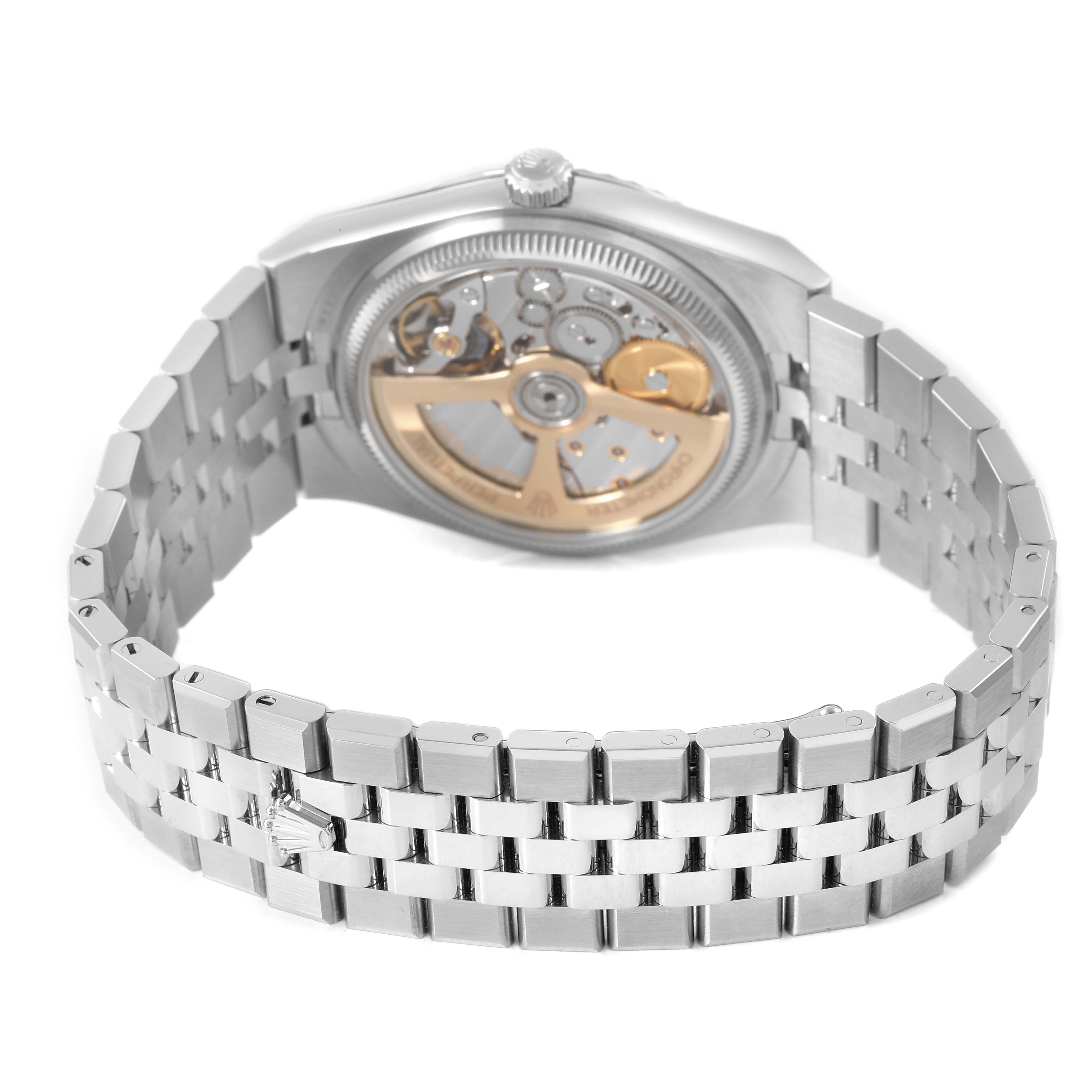The Rolex Land-Dweller watch is shown from the back, highlighting its open case back and metallic bracelet.