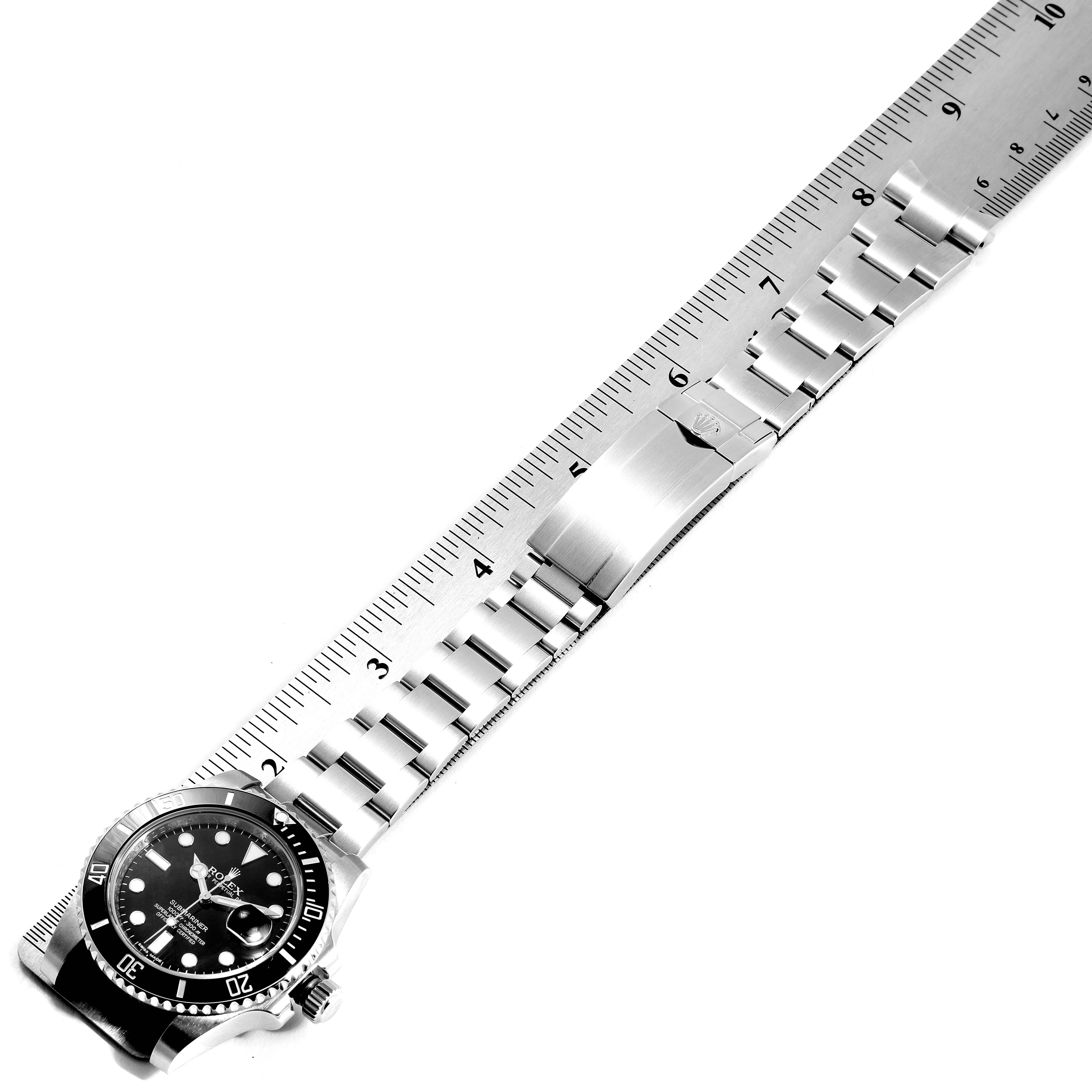 The image shows a top view of a Rolex Submariner 116610 Men
s Stainless Steel Black Dial 116610 Men
s Stainless Steel Black Dial watch with a visible bezel, dial, and bracelet laid next to a ruler.