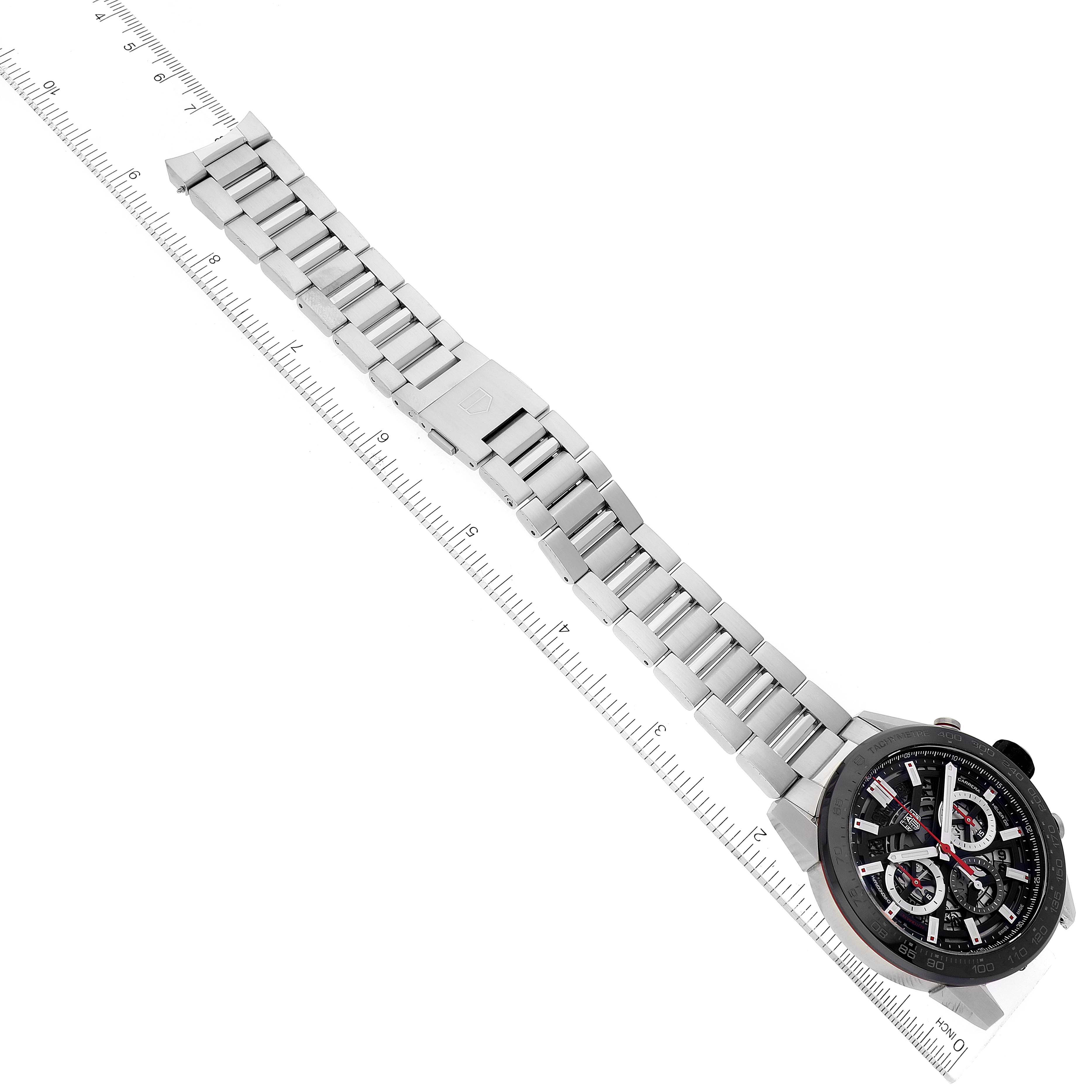The image shows a Tag Heuer Carrera CBG2A10.BA0654 Men's Stainless Steel  CBG2A10.BA0654 Men's Stainless Steel  watch laid flat, featuring its face and metal bracelet against a ruler.