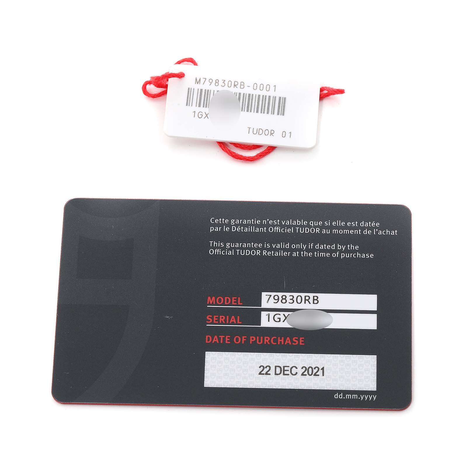 The image shows a warranty card and tag for the Tudor Heritage Black Bay 79830RB Men
s Stainless Steel Black Dial 79830RB Men
s Stainless Steel Black Dial model 79830RB, along with a serial number and purchase date.