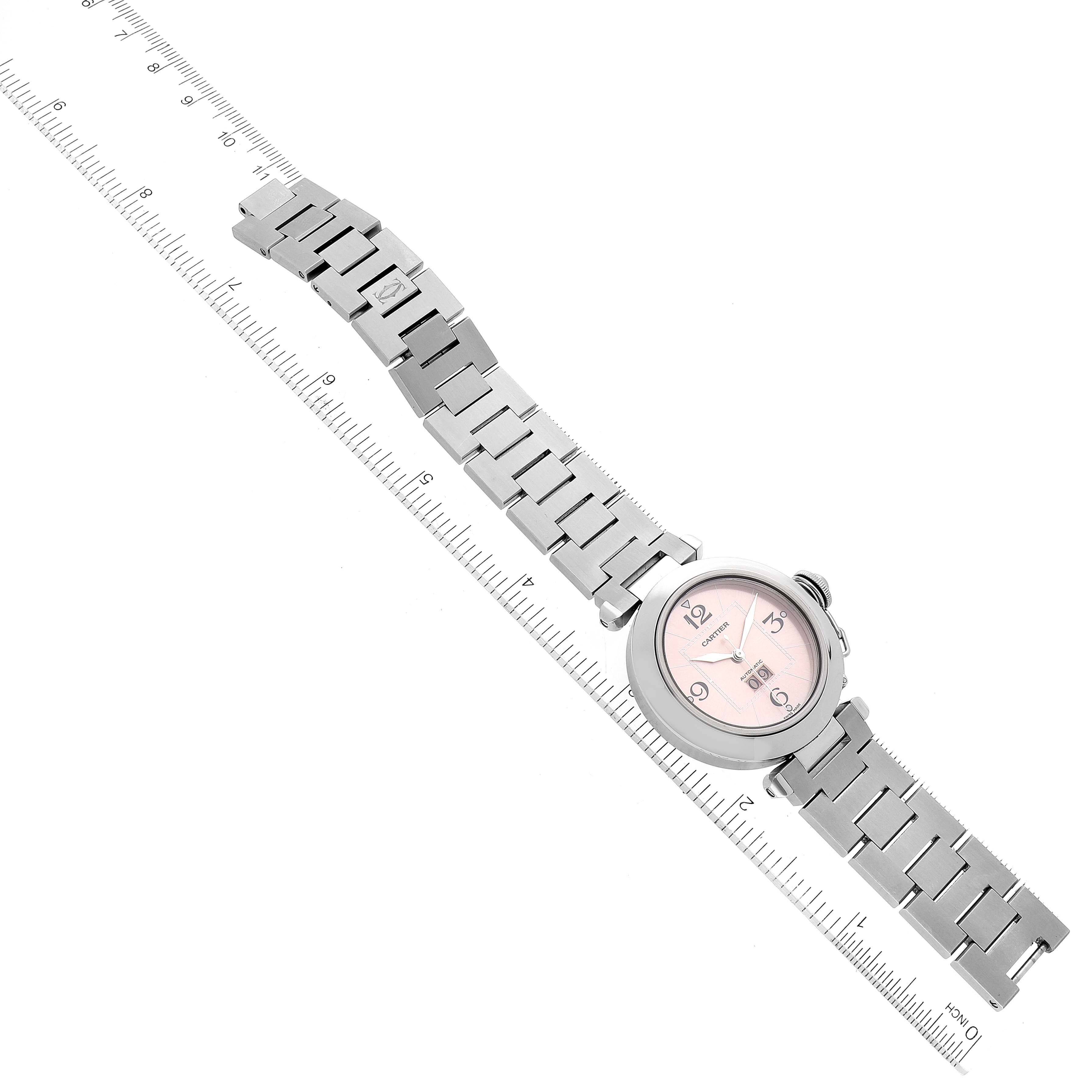 The Cartier Pasha W31058M7 Women's Stainless Steel Pink Dial W31058M7 Women's Stainless Steel Pink Dial watch is shown from an overhead angle, displaying the face, case, and metal bracelet alongside a ruler for size reference.