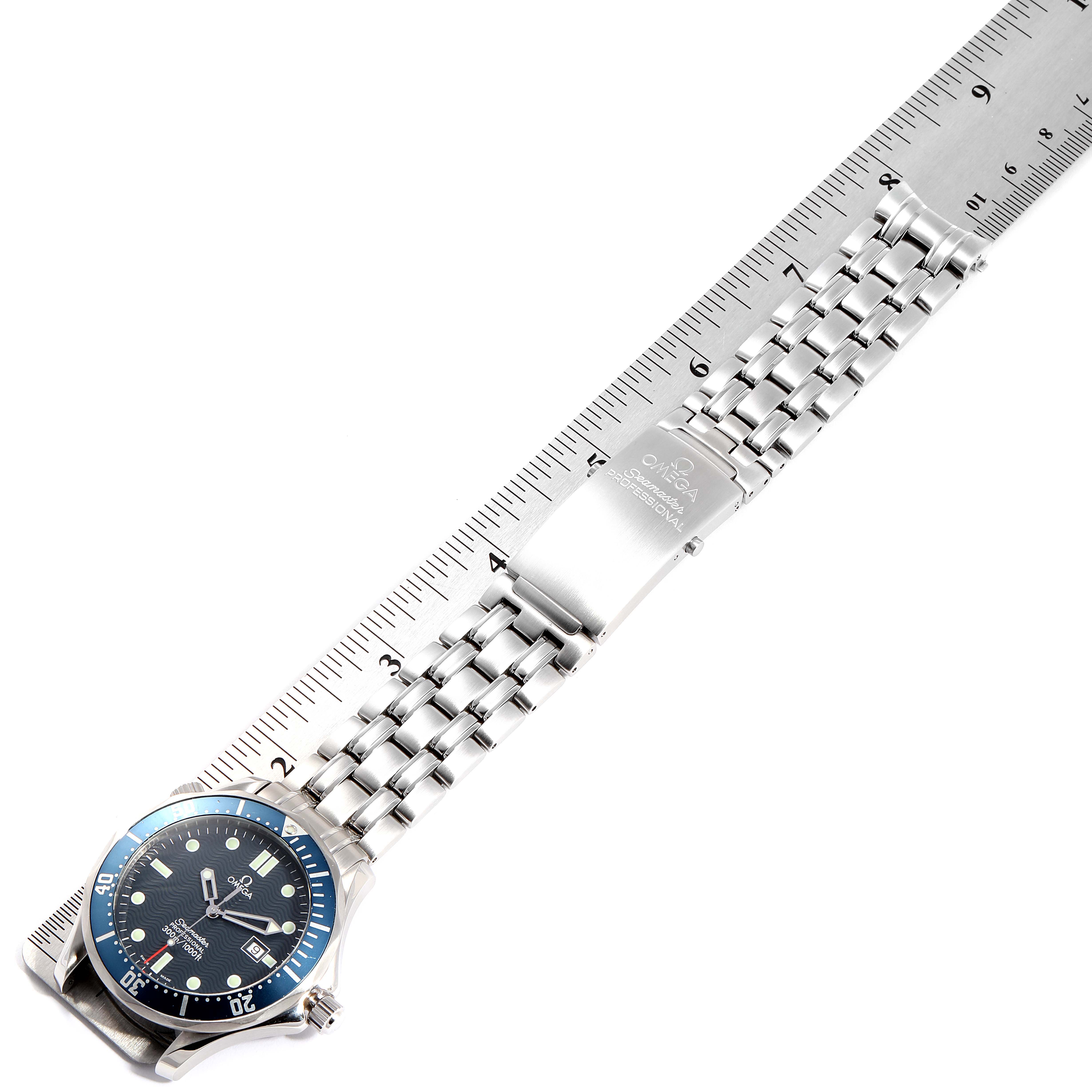 The image shows the Omega Seamaster 2541.80.00 Men
s Stainless Steel Blue Dial 2541.80.00 Men
s Stainless Steel Blue Dial watch laid flat with a ruler beside it, displaying the watch face and metal bracelet.
