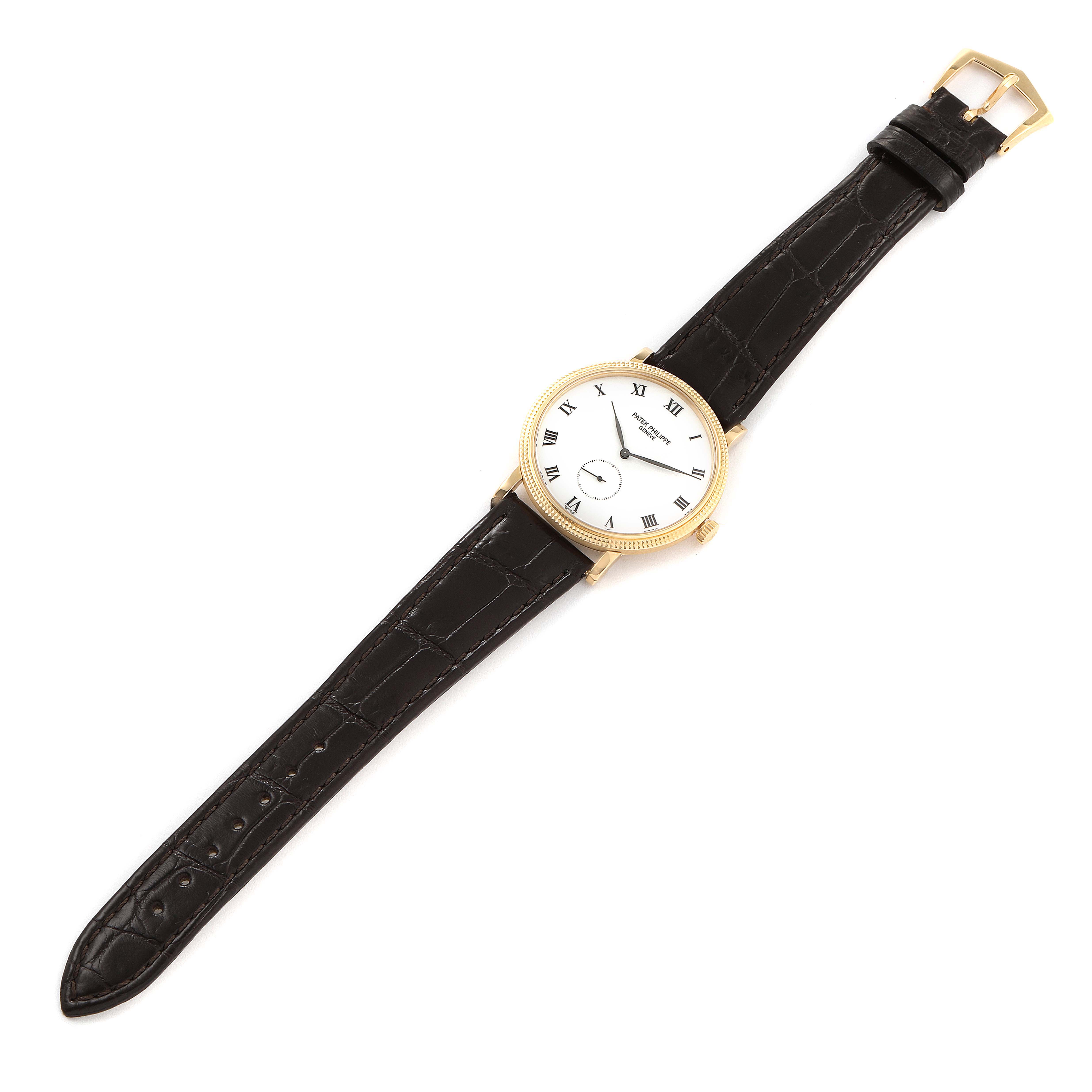 The Patek Philippe Calatrava 3919J Men's Yellow Gold White Dial 3919J Men's Yellow Gold White Dial watch is shown lying flat, displaying its round face, black leather strap, and gold buckle.