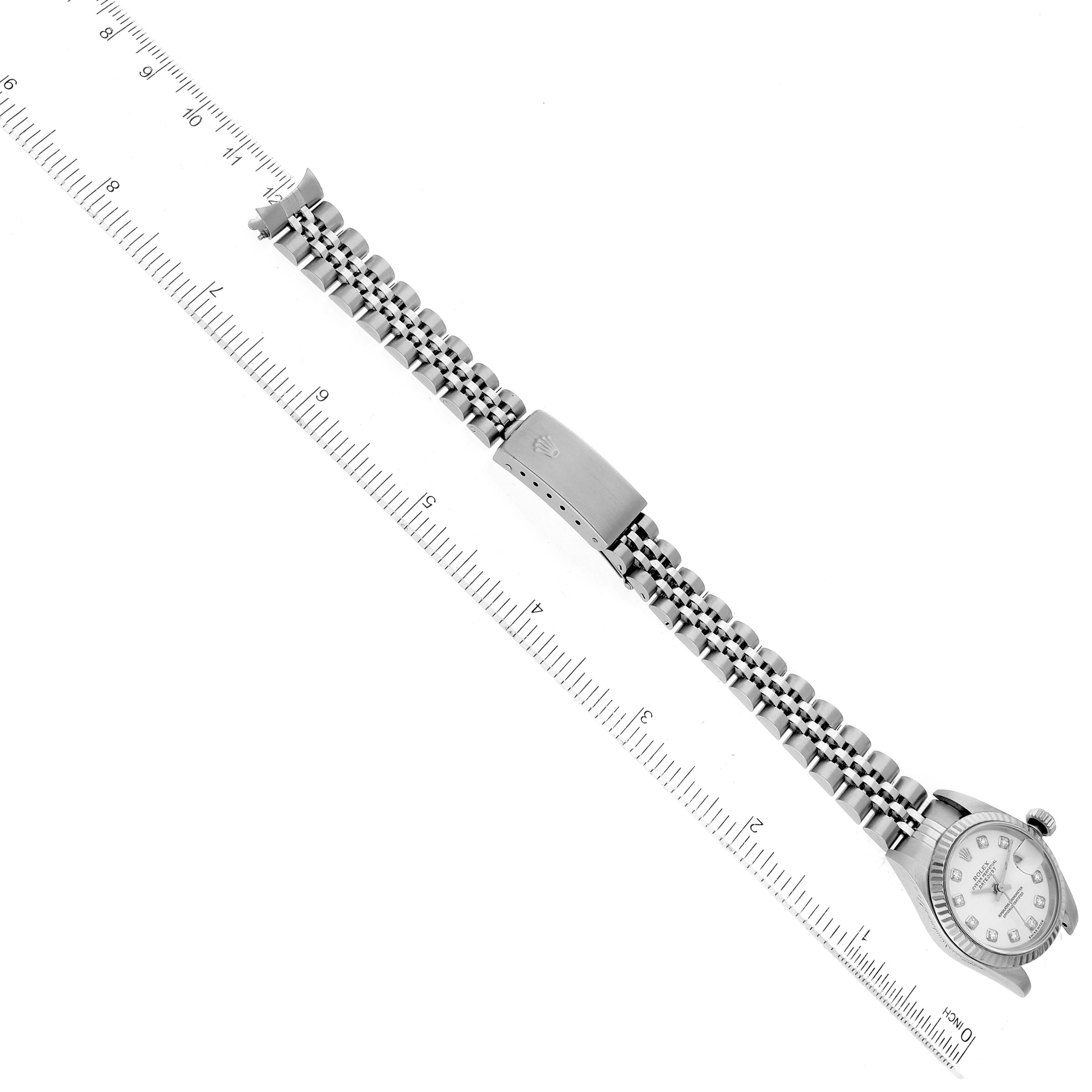 The image shows a top-down view of a Rolex Datejust 79174 Women's Stainless Steel White Dial 79174 Women's Stainless Steel White Dial watch with its face, bracelet, and clasp laid beside a ruler.