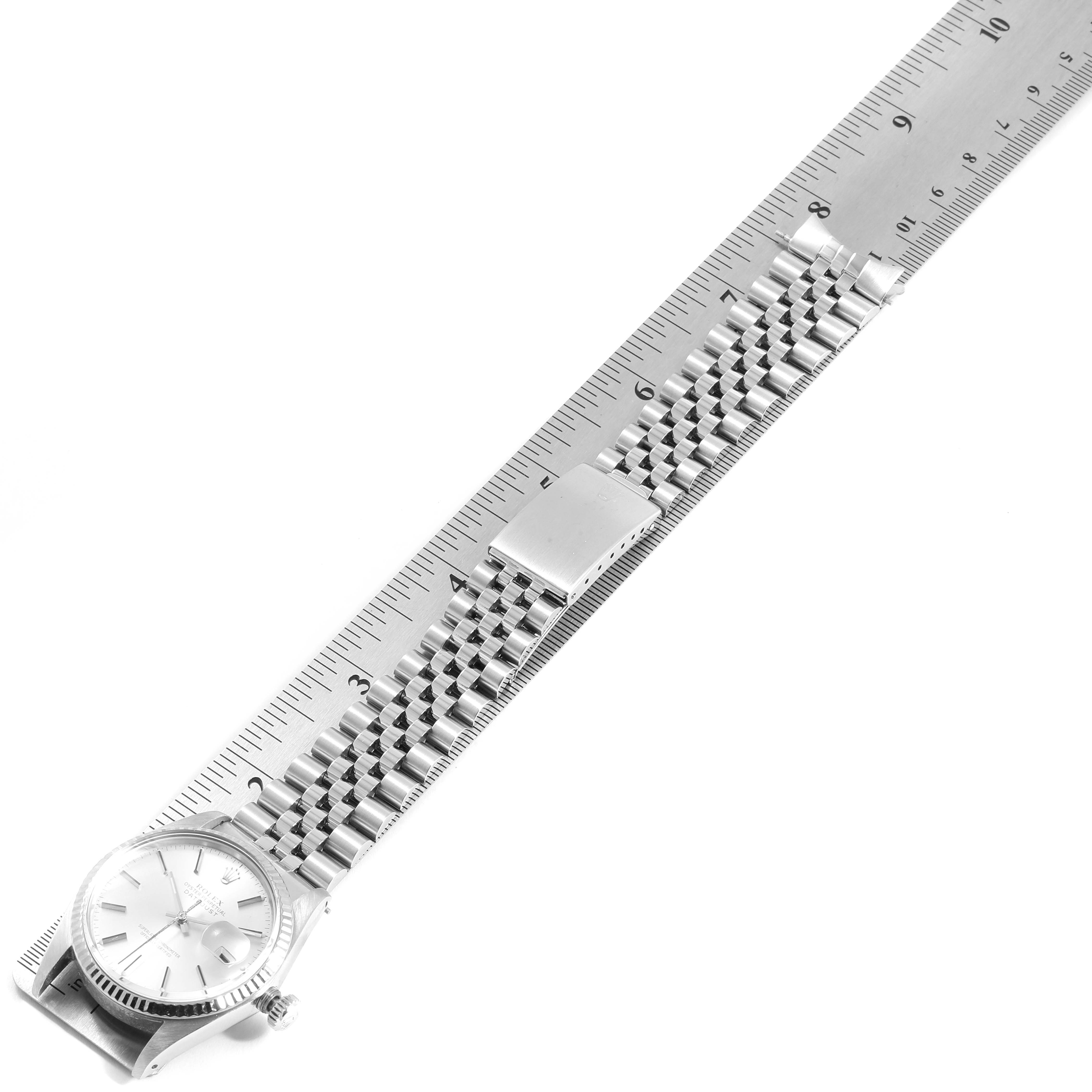 The image shows a Rolex Datejust 16014 Men
s Stainless Steel Silver Dial 16014 Men
s Stainless Steel Silver Dial watch, displayed flat beside a ruler, highlighting the watch face, bracelet, and clasp.