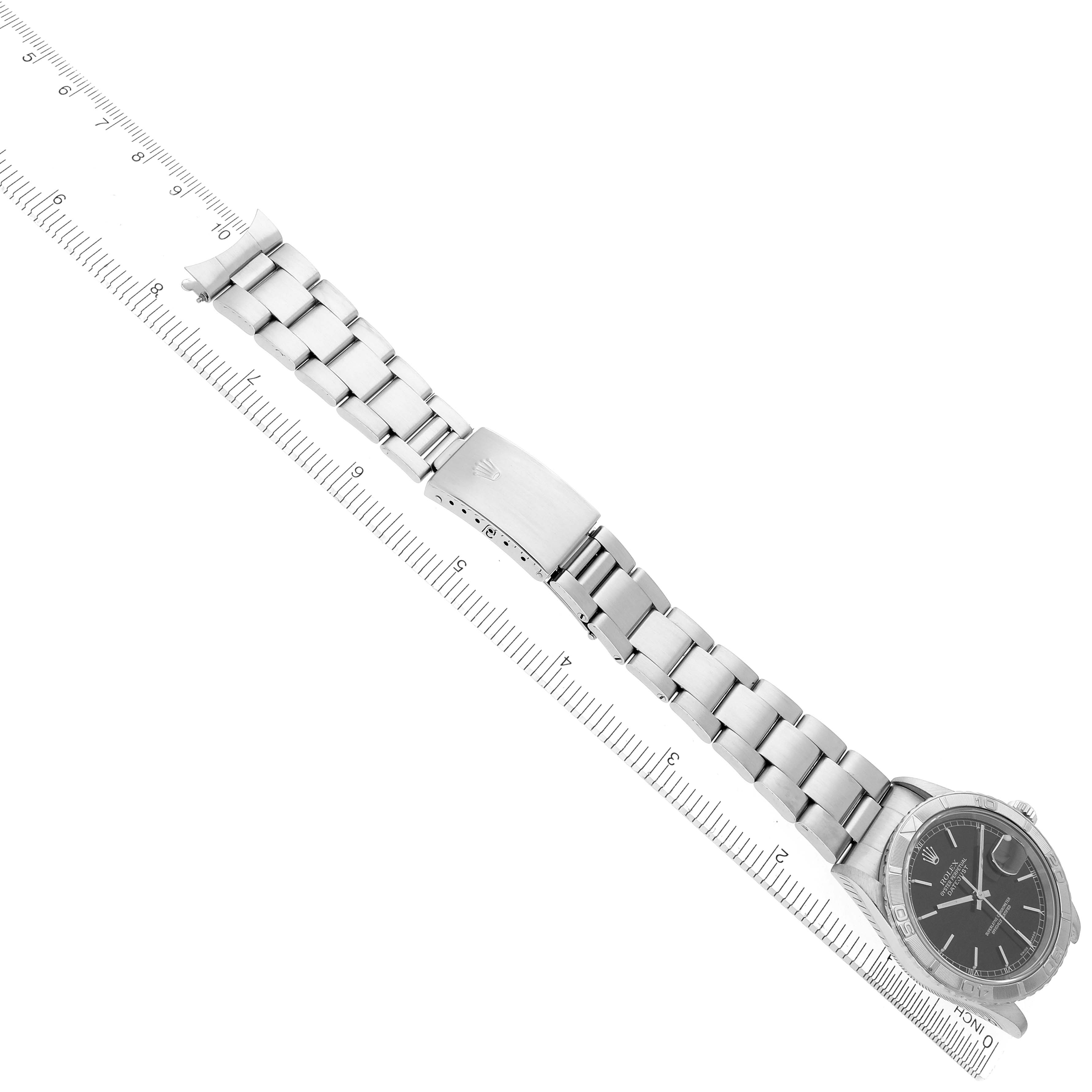 The image shows a Rolex Turn-o-Graph 16264 Men's Stainless Steel Black Dial 16264 Men's Stainless Steel Black Dial watch from an aerial view, displaying the bracelet, clasp, and face diagonally with a ruler for scale.