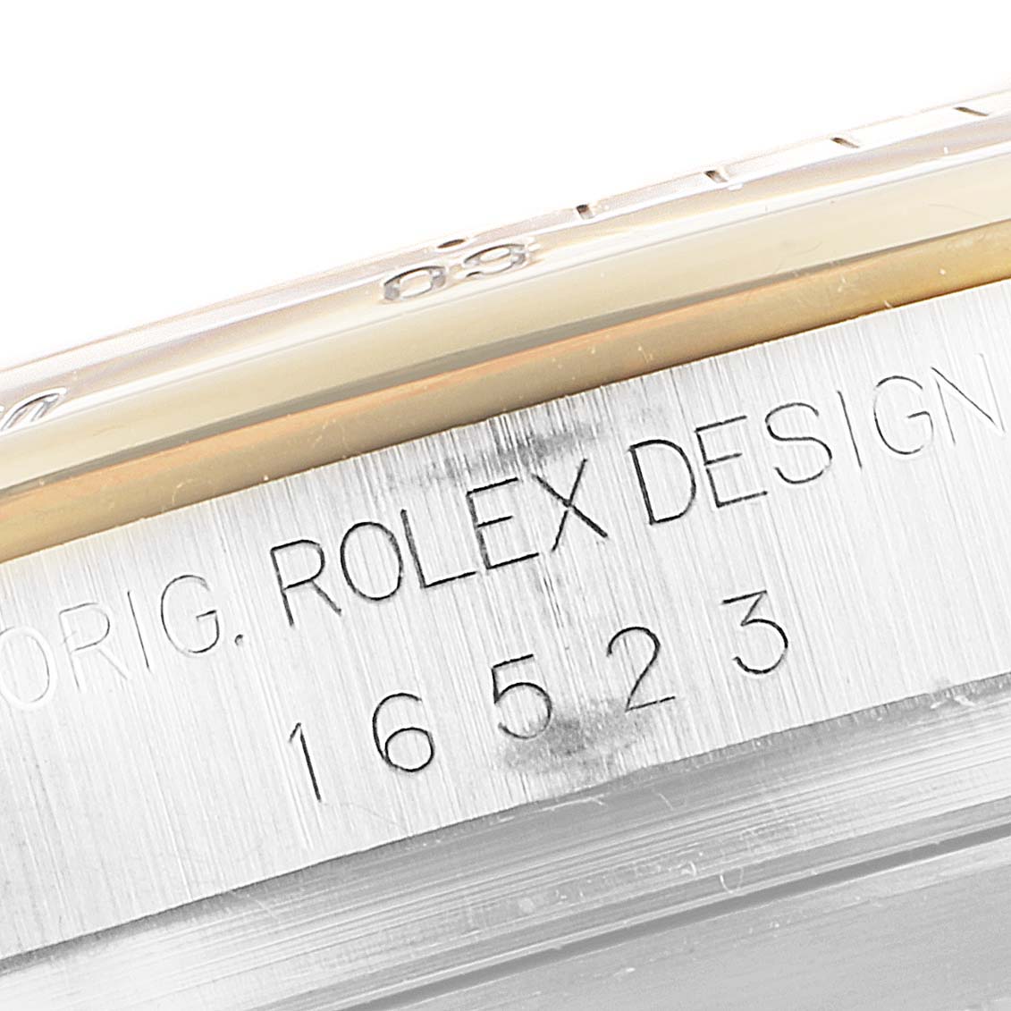 This close-up image shows the side of a Rolex Daytona 16523 Men's Steel and Gold (two tone) Black Dial 16523 Men's Steel and Gold (two tone) Black Dial watch, featuring the engraved design and model number "16523."