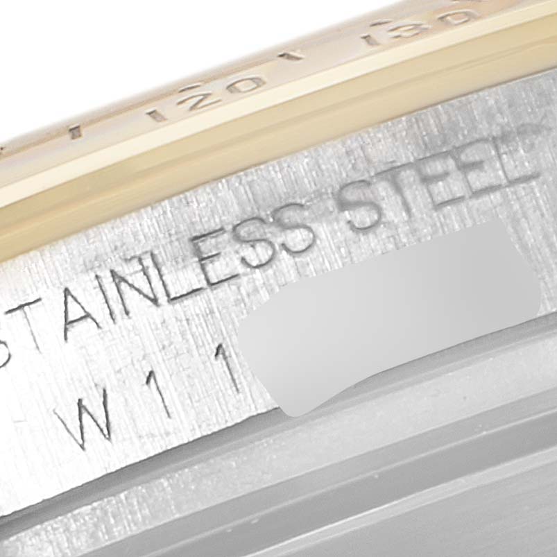 The image shows a close-up of the Rolex Daytona 16523 Men's Steel and Gold (two tone) Black Dial 16523 Men's Steel and Gold (two tone) Black Dial watch's case with "STAINLESS STEEL" and part of the bezel visible.