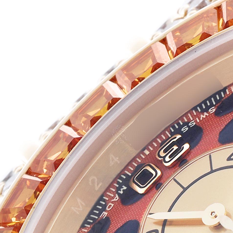The image shows a close-up of the bezel and dial of a Rolex Daytona 116598 Men's Yellow Gold Orange Dial 116598 Men's Yellow Gold Orange Dial with a jeweled edge.