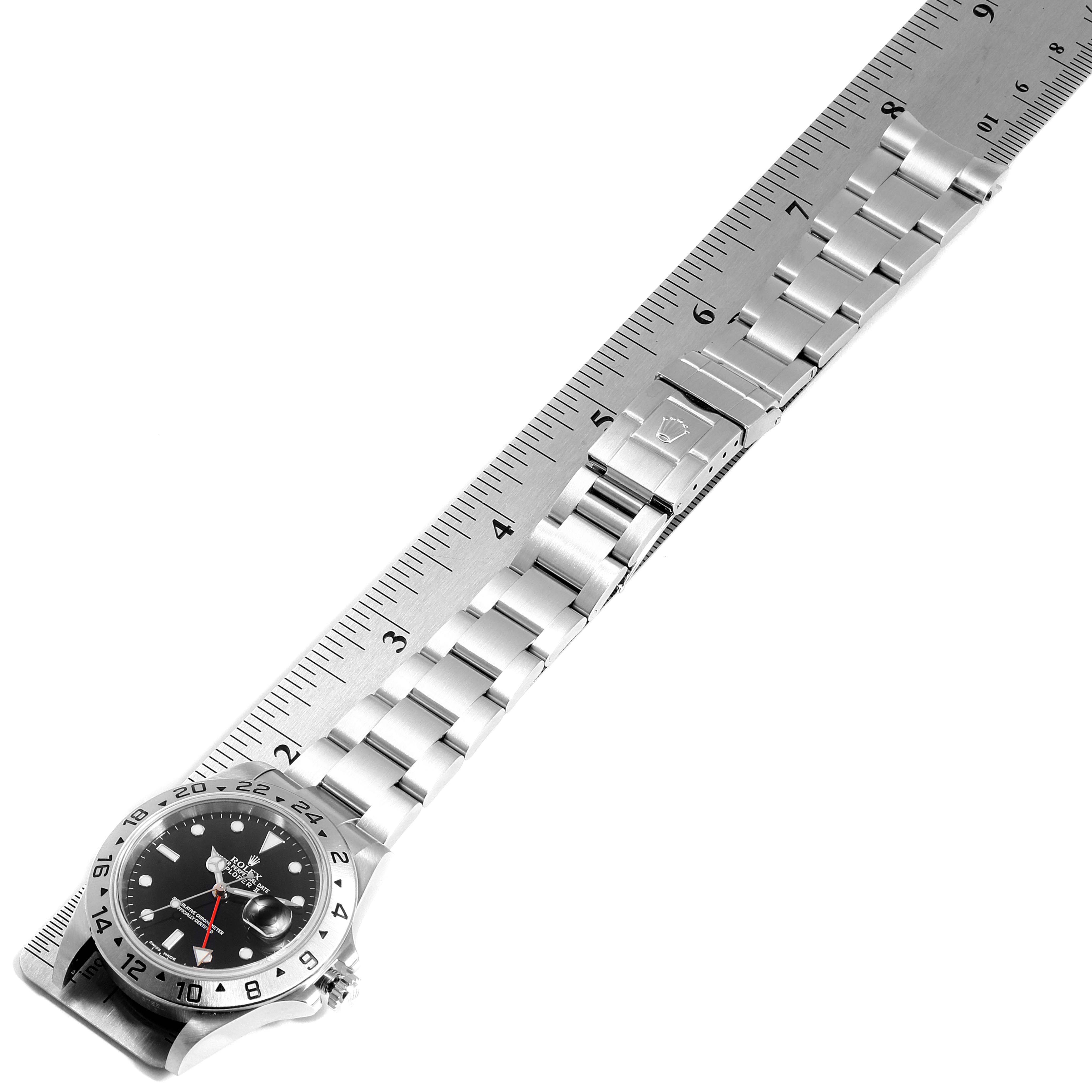 The Rolex Explorer 16570 Men
s Stainless Steel Black Dial 16570 Men
s Stainless Steel Black Dial watch is shown from a top-down angle, highlighting its face, bezel, and metal bracelet alongside a ruler.