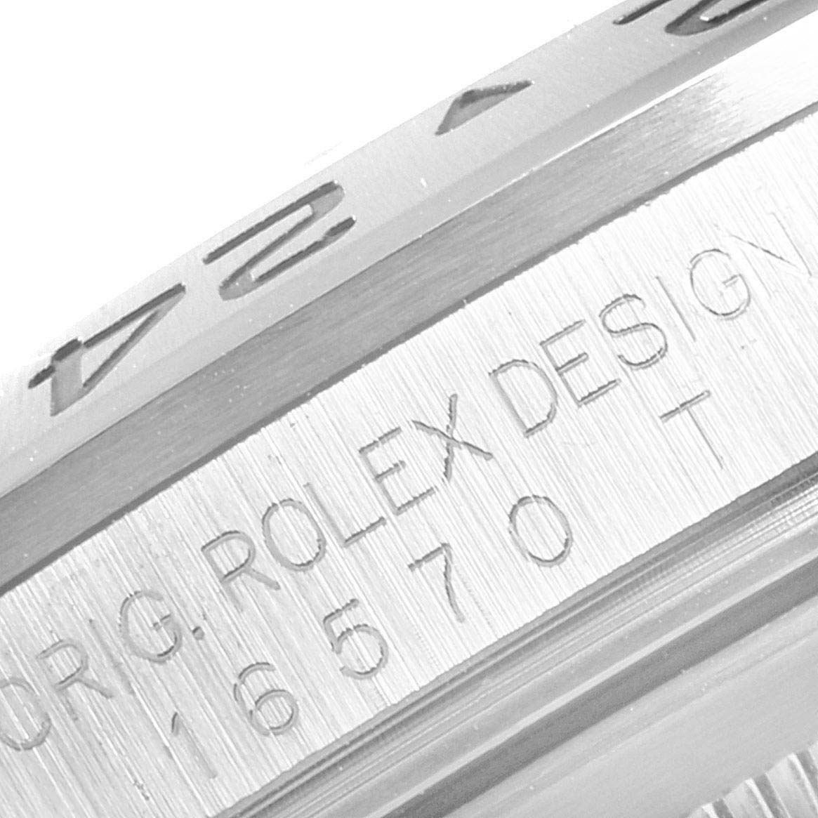 The image shows a close-up of Rolex Explorer 16570 Men
s Stainless Steel Black Dial 16570 Men
s Stainless Steel Black Dial model
s bezel and engraved case serial number.