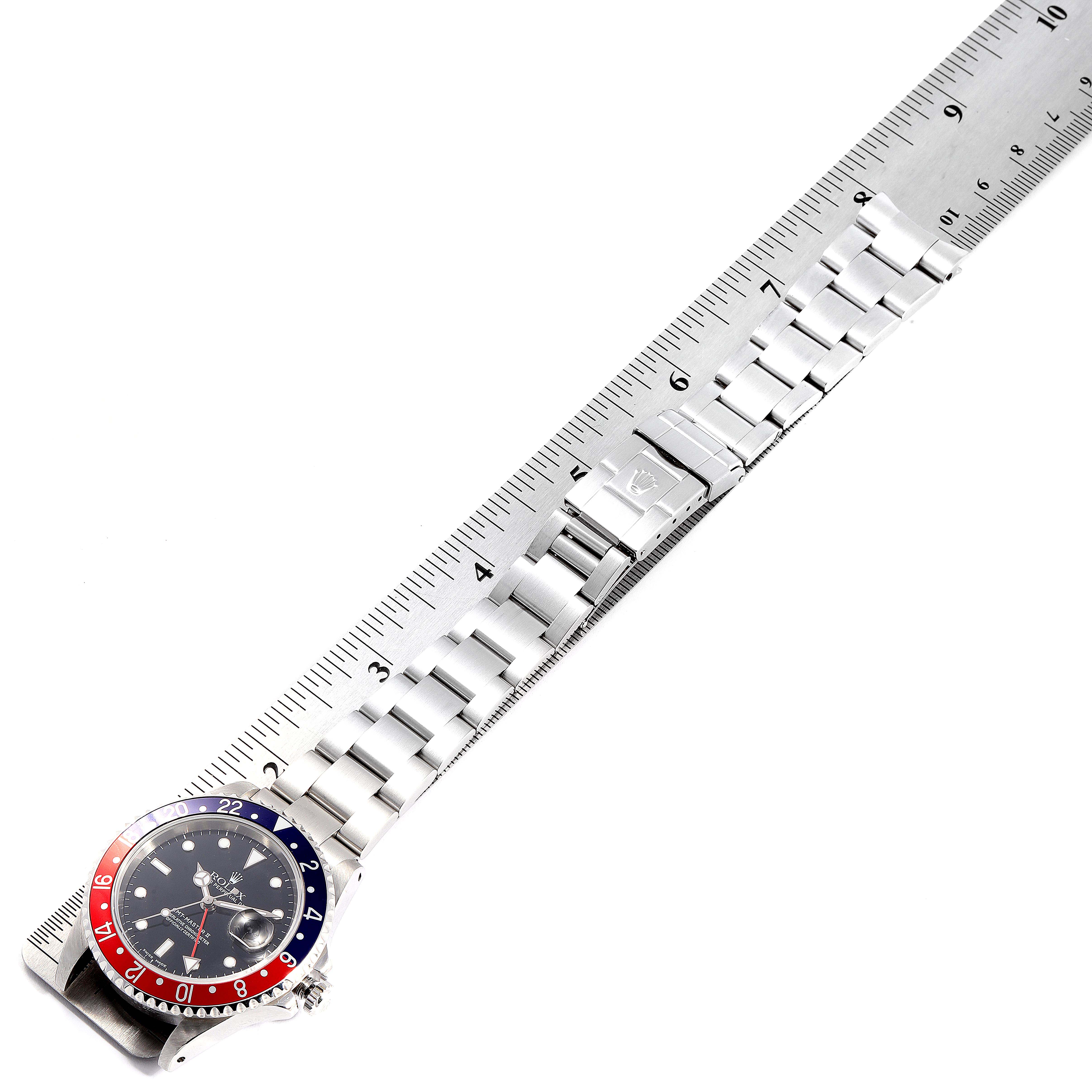 The Rolex GMT-Master 16710 Men's Stainless Steel Black Dial 16710 Men's Stainless Steel Black Dial watch is shown from a top-down angle, displaying the face, bezel, and bracelet along a ruler.