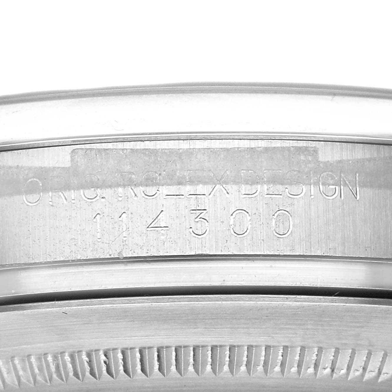 This image shows a close-up of the serial number engraving on the case of a Rolex Oyster Perpetual 114300 Men's Stainless Steel Blue Dial 114300 Men's Stainless Steel Blue Dial watch.