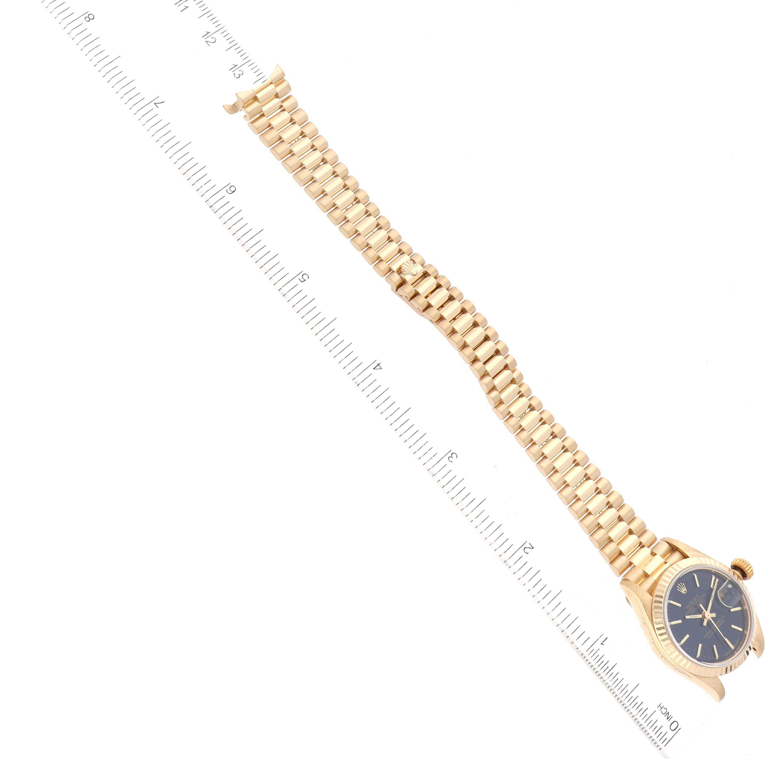 The image shows a Rolex President 79178 Women's Yellow Gold Blue Dial 79178 Women's Yellow Gold Blue Dial model watch with its full gold bracelet laid flat and a ruler for scale.
