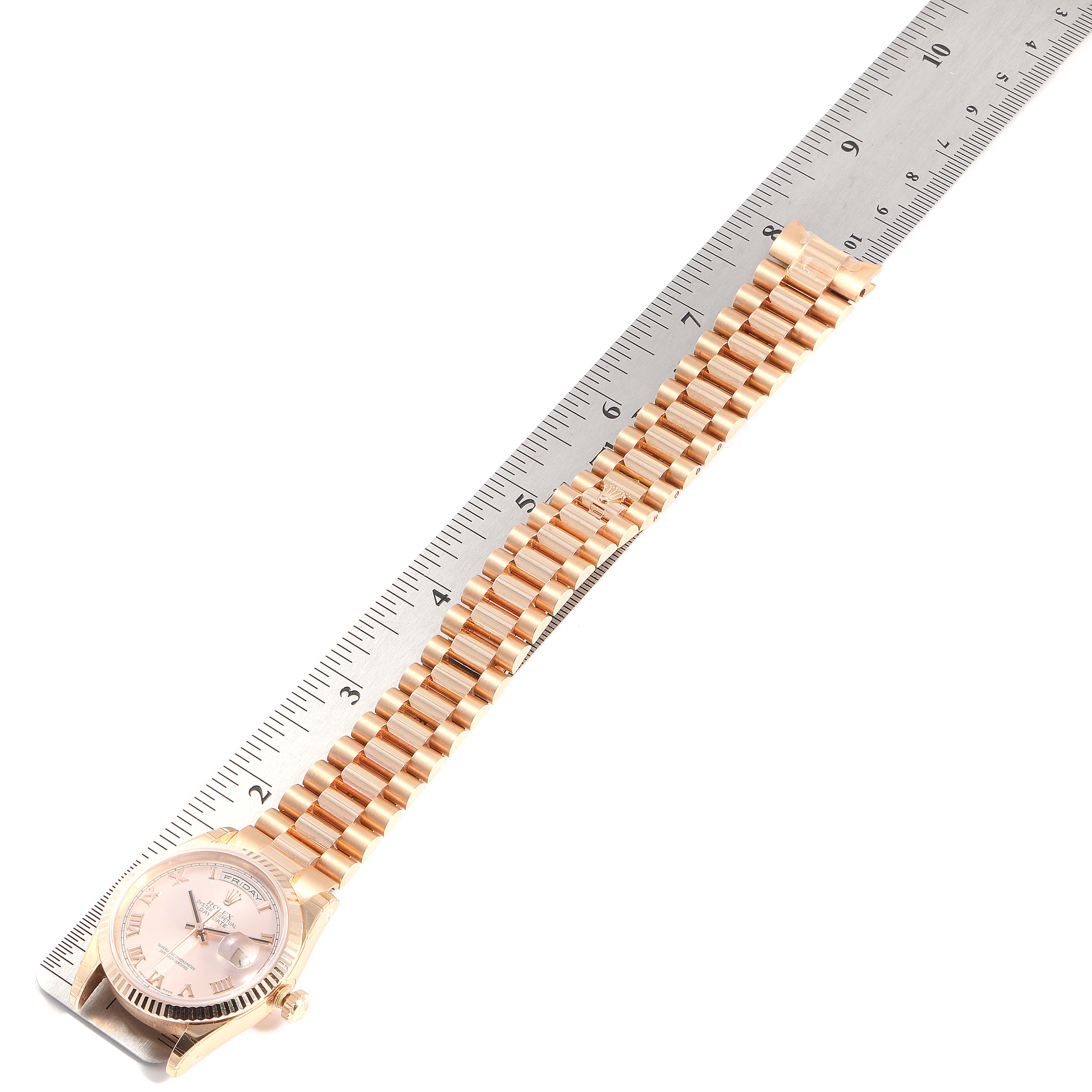 The image shows a Rolex President 118235 Men's Rose Gold Pink Dial 118235 Men's Rose Gold Pink Dial model watch laid flat next to a ruler, with the watch face and bracelet visible.