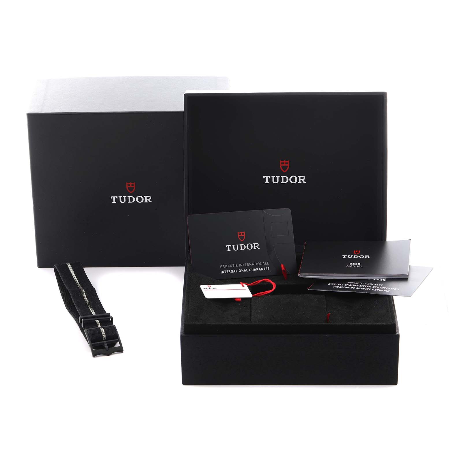 The Tudor Heritage Black Bay 79030B Men's Stainless Steel Blue Dial 79030B Men's Stainless Steel Blue Dial watch packaging is shown with an open box, manuals, warranty card, and an extra strap displayed at an angle.