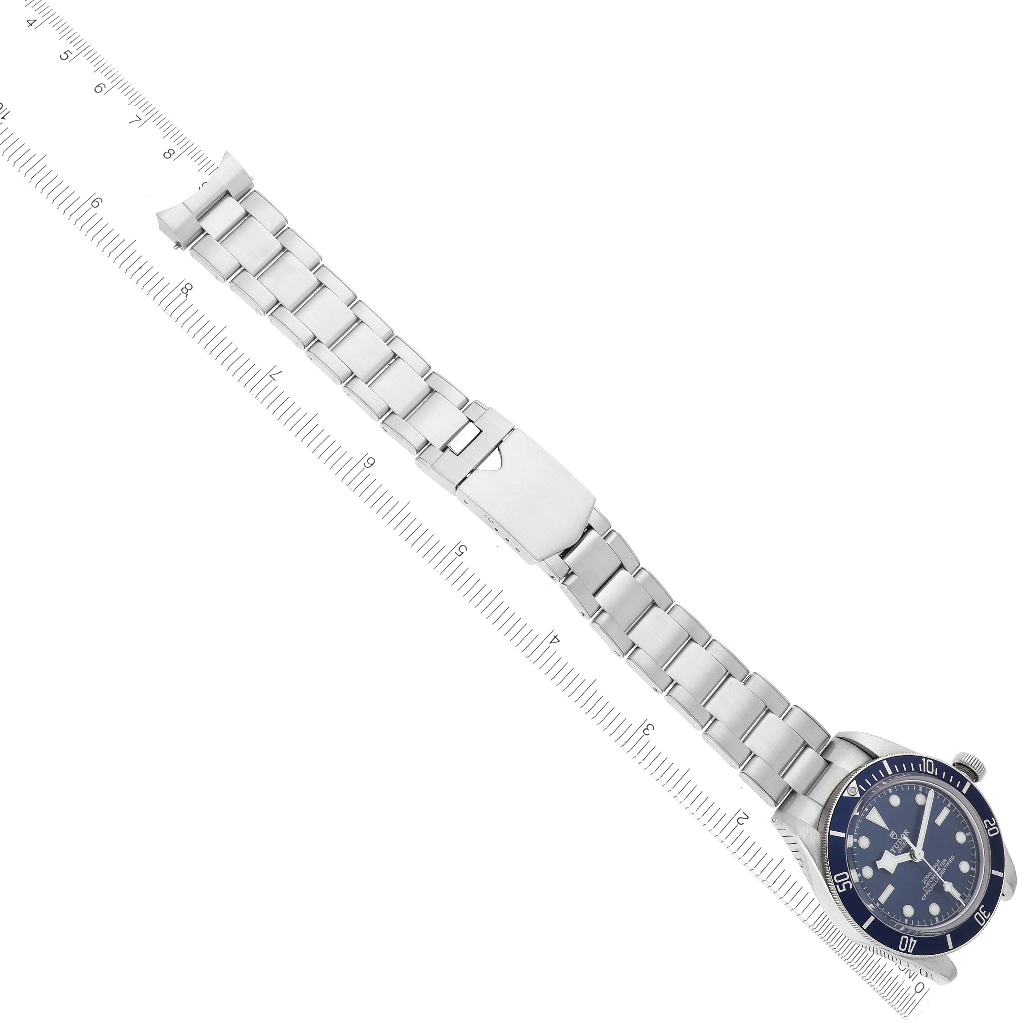 The image shows a Tudor Heritage Black Bay 79030B Men's Stainless Steel Blue Dial 79030B Men's Stainless Steel Blue Dial watch at an angle displaying the dial, bezel, and metal bracelet alongside a ruler.
