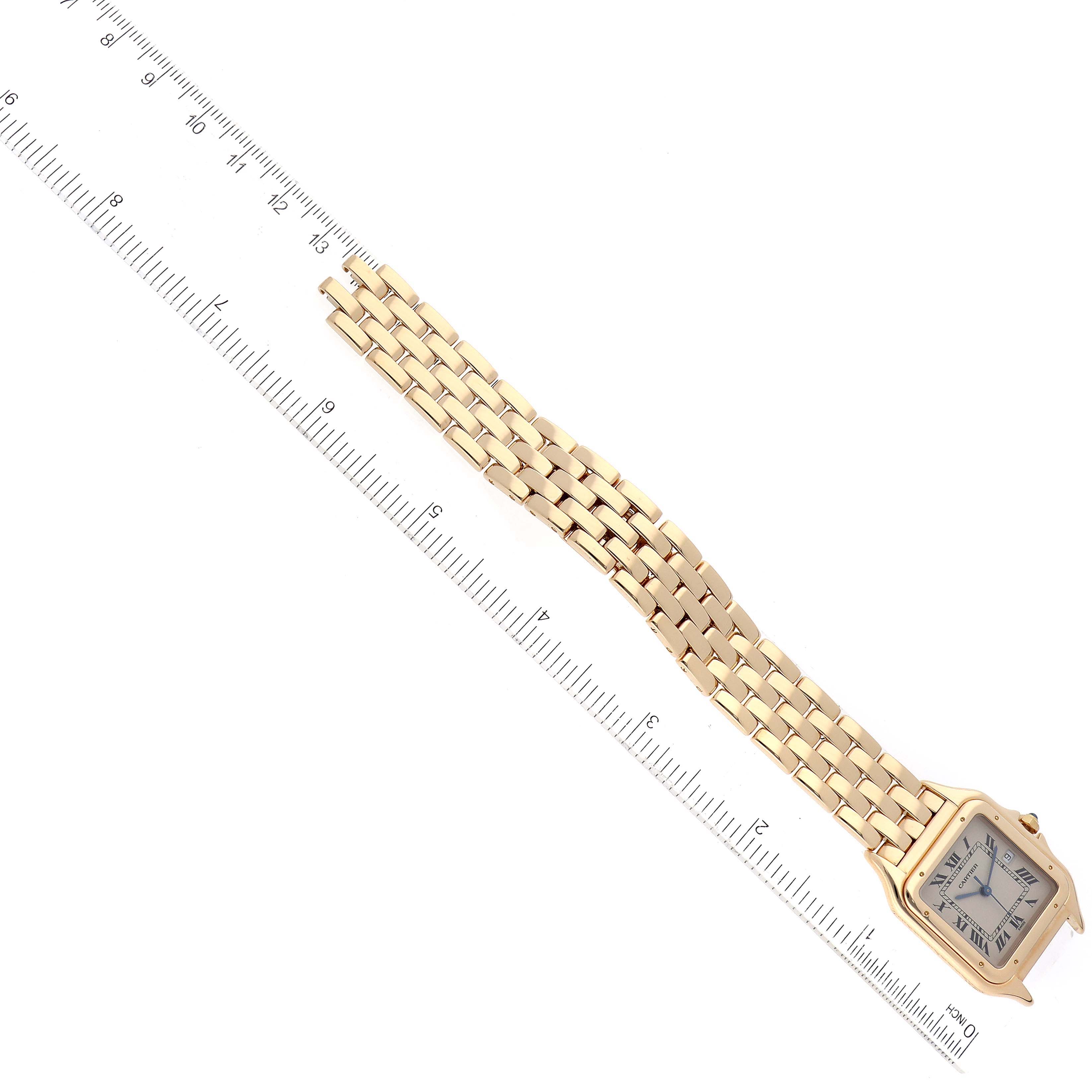 The image shows a top-down view of a Cartier Panthere W25014B9 Men's Yellow Gold Silver Dial W25014B9 Men's Yellow Gold Silver Dial watch, highlighting its linked gold bracelet and face next to a ruler.