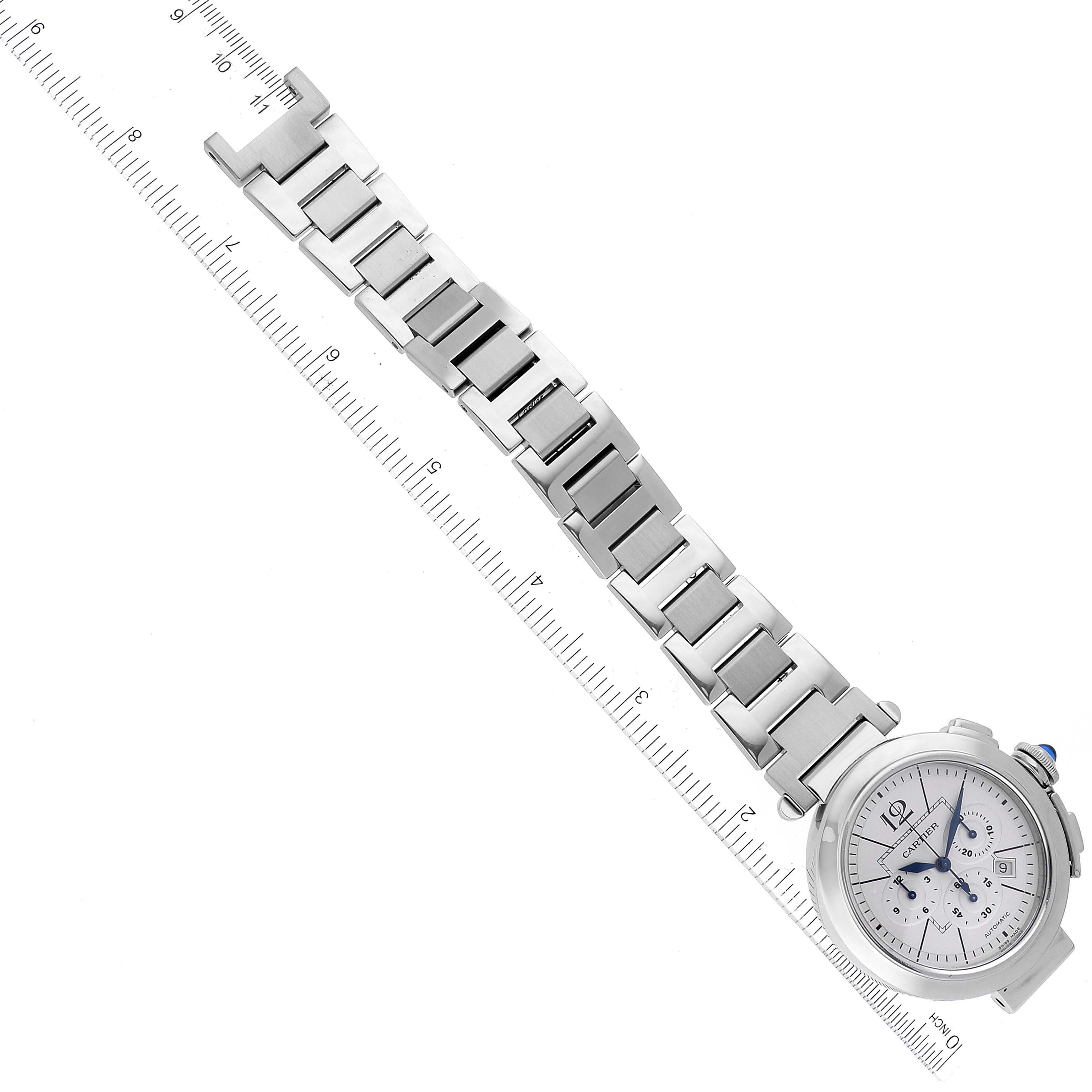 The image shows a Cartier Pasha W31085M7 Men's Stainless Steel Silver Dial W31085M7 Men's Stainless Steel Silver Dial watch lying flat, displaying its face, bracelet, and part of the crown, alongside a measuring ruler.