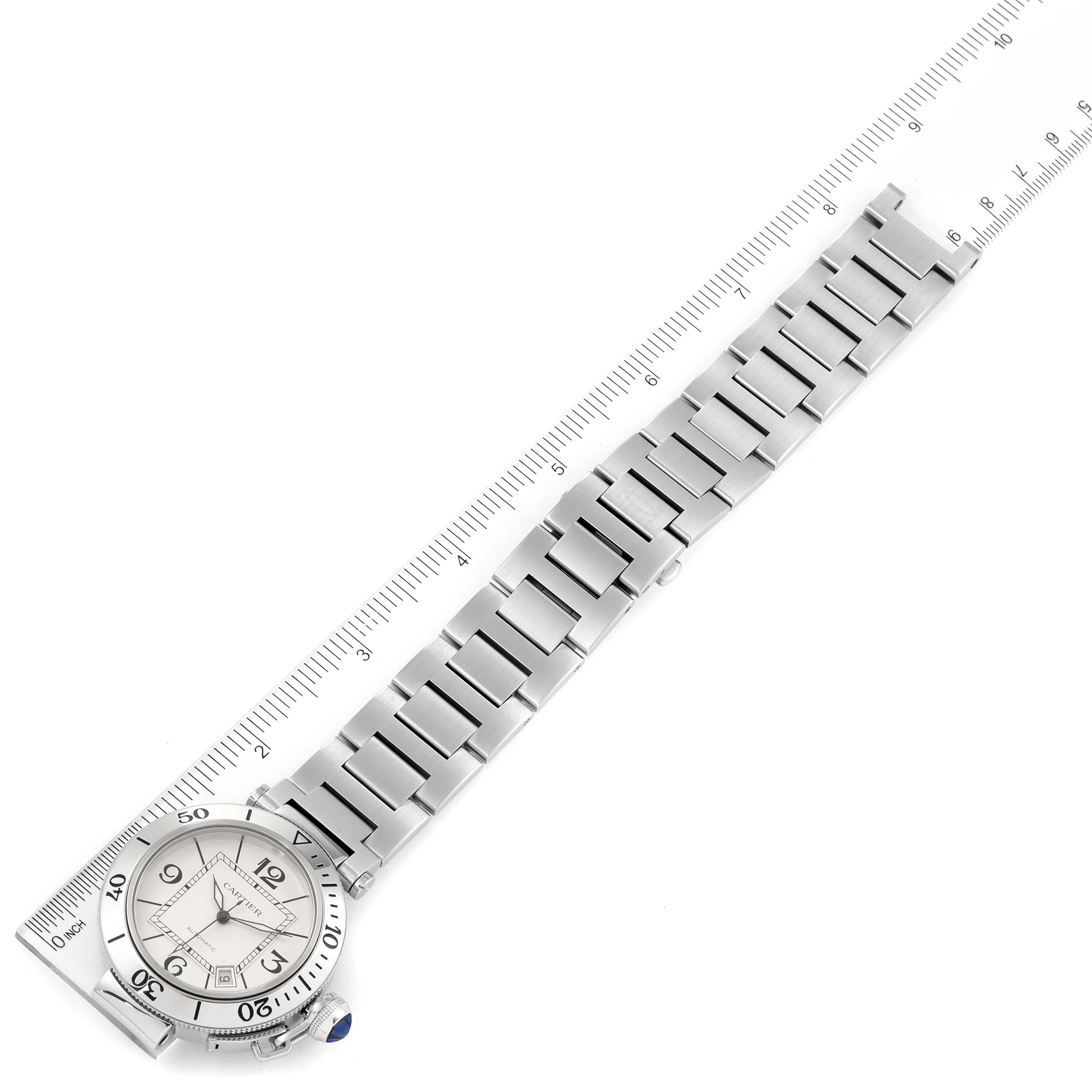 The image shows an aerial view of the Cartier Pasha W31080M7 Men's Stainless Steel Silver Dial W31080M7 Men's Stainless Steel Silver Dial watch, highlighting its face, bezel, bracelet, and a measuring ruler beside it.