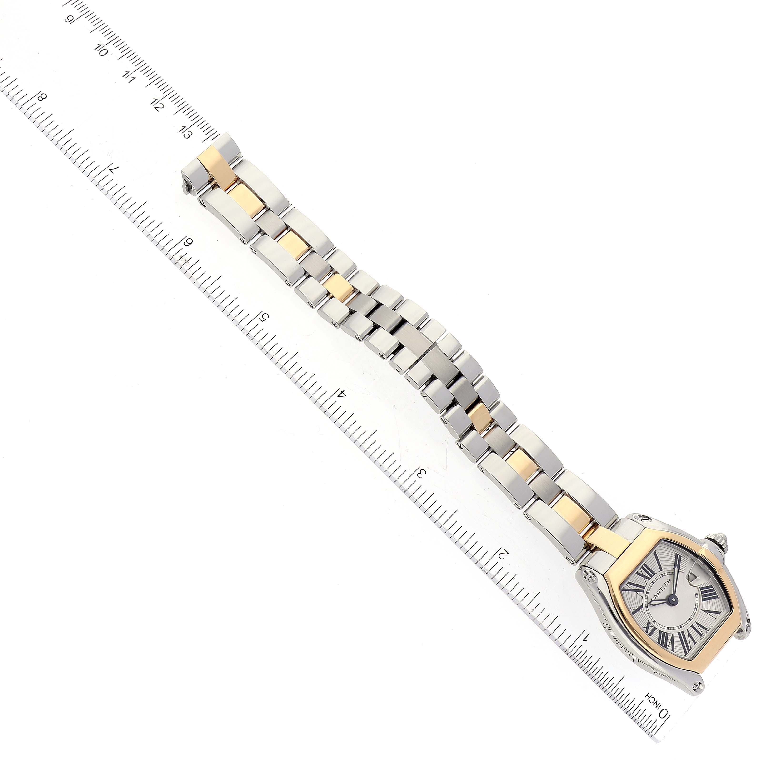 The Cartier Roadster W62026Y4 Women's Steel and Gold (two tone) Silver Dial W62026Y4 Women's Steel and Gold (two tone) Silver Dial watch is shown from an overhead angle, highlighting the face, bracelet, and a ruler indicating its length.