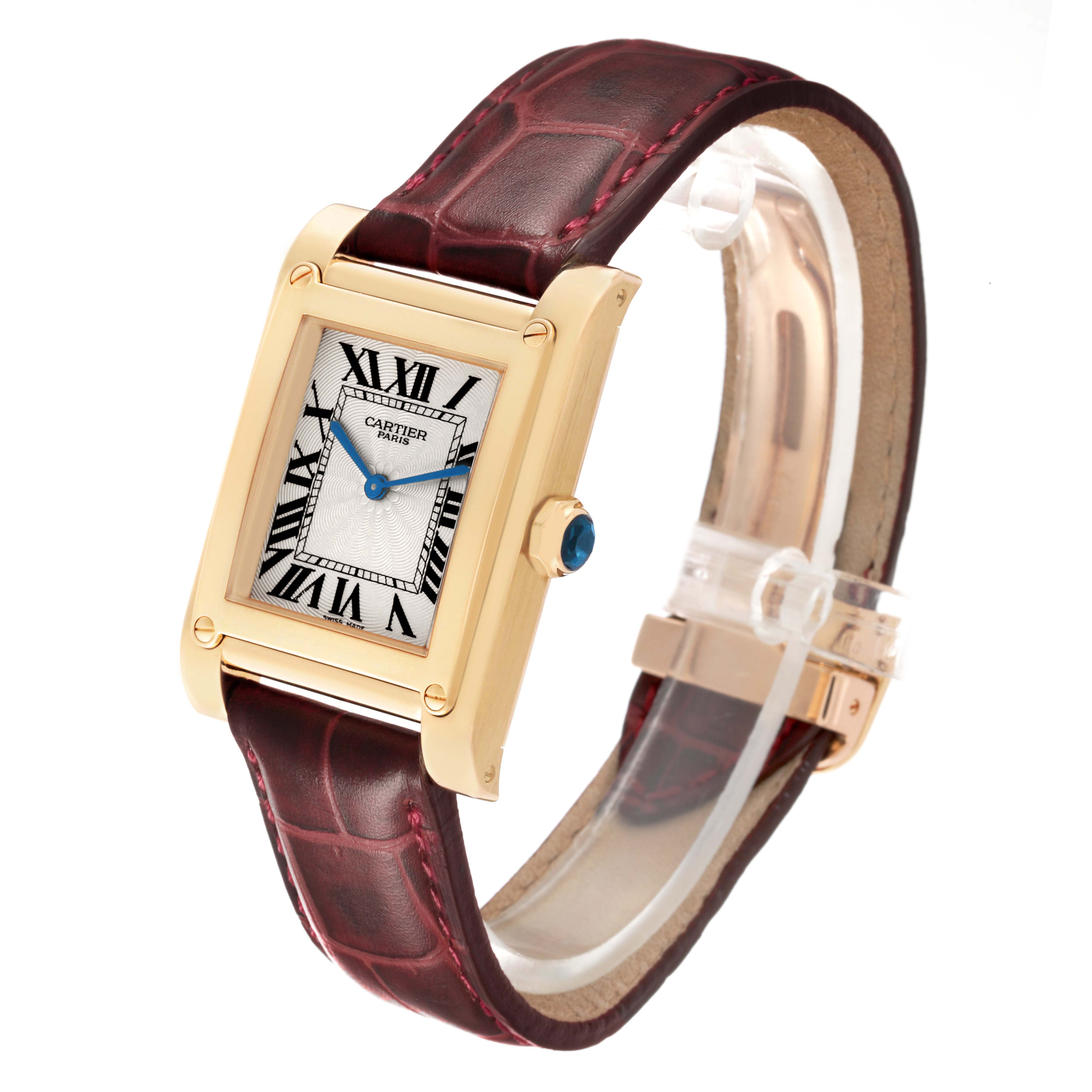 The Cartier Tank A Vis W1529451 Men's Yellow Gold Silver Dial watch is shown in a three-quarter view, highlighting its rectangular face, leather strap, and crown.