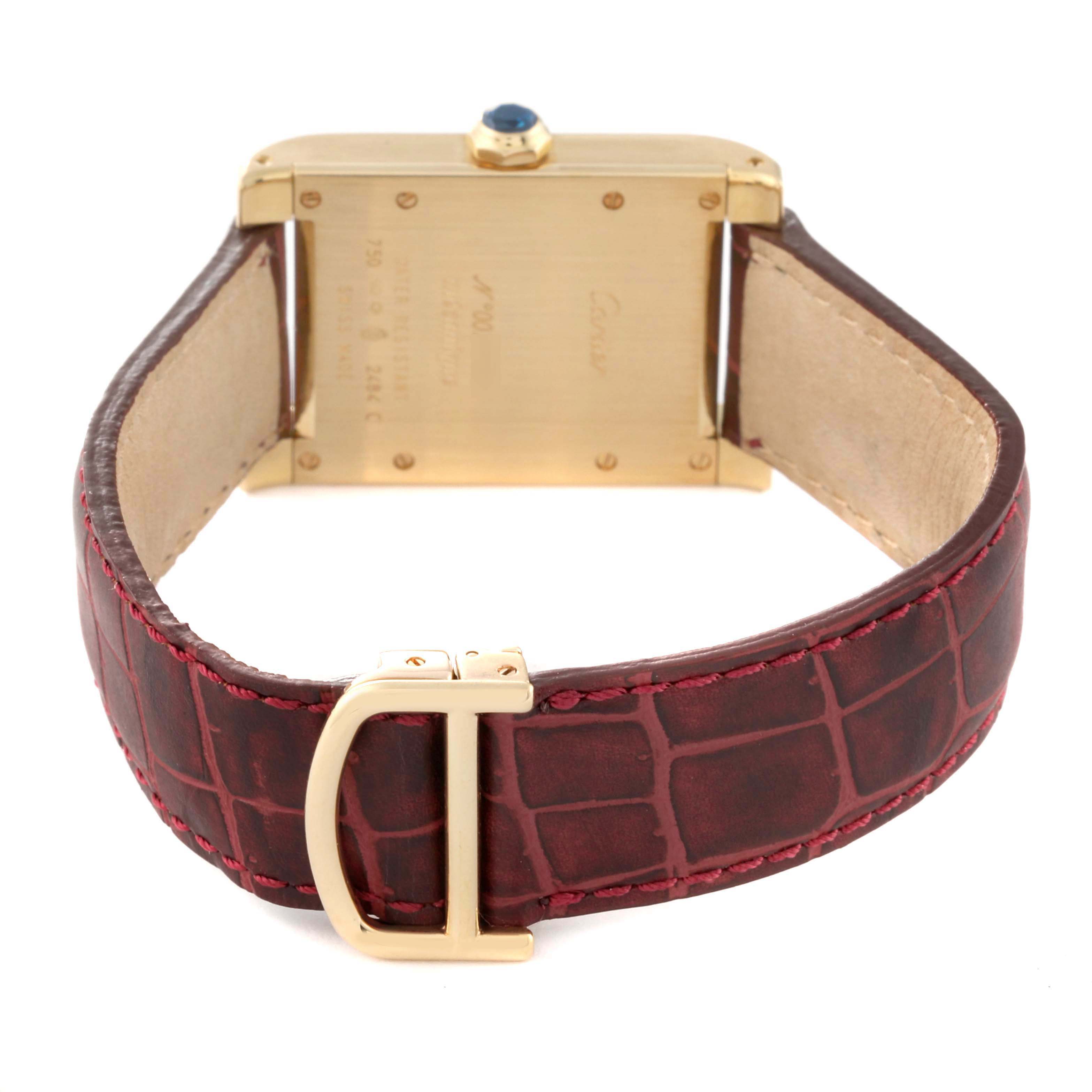 The Cartier Tank à Vis watch is shown from the back, highlighting the case, crown, and leather strap with a buckle.