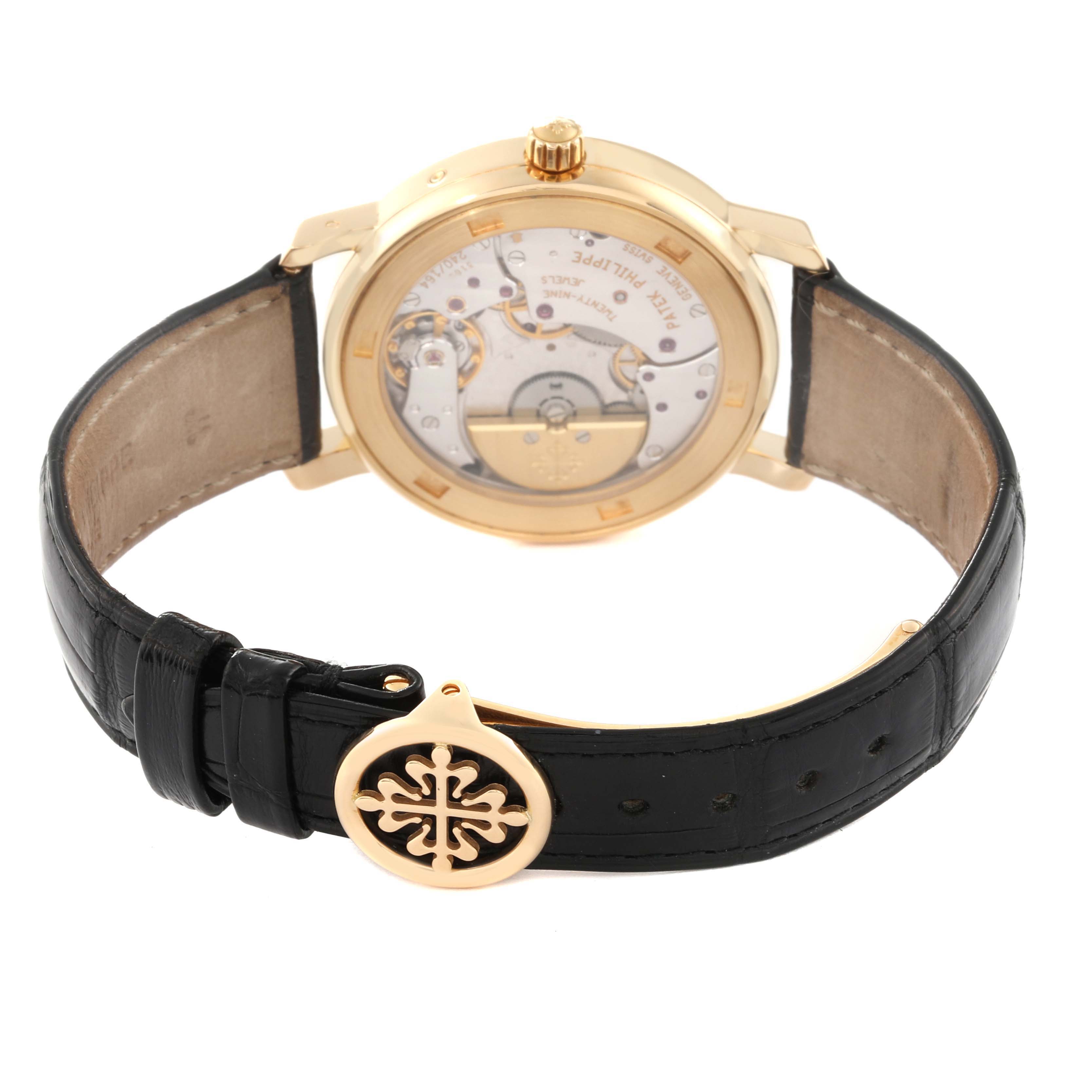 The image shows the back view of a Patek Philippe Complications 5055J-001 Men
s Yellow Gold White Dial 5055J-001 Men
s Yellow Gold White Dial model watch, highlighting its internal mechanism and leather strap.