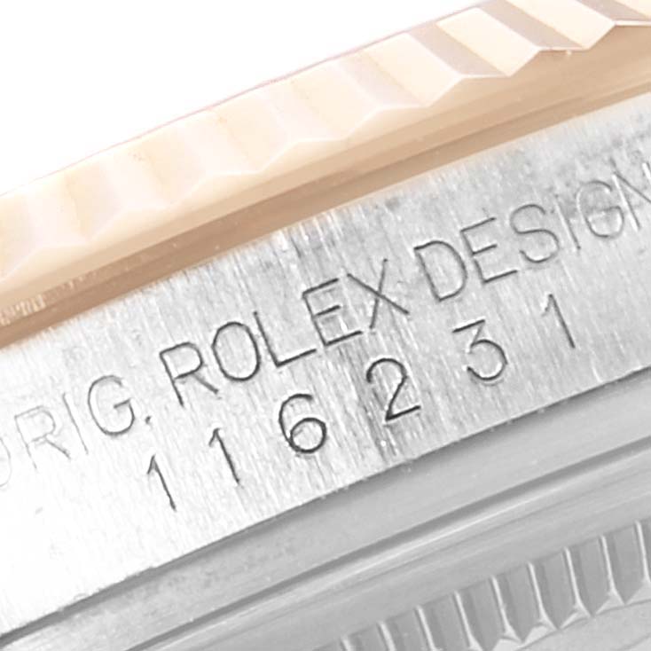 This close-up image of a Rolex Datejust 116231 Men's Steel and Gold (two tone) White Dial 116231 Men's Steel and Gold (two tone) White Dial watch shows part of the fluted bezel and the "ROLEX DESIGN" engraving.