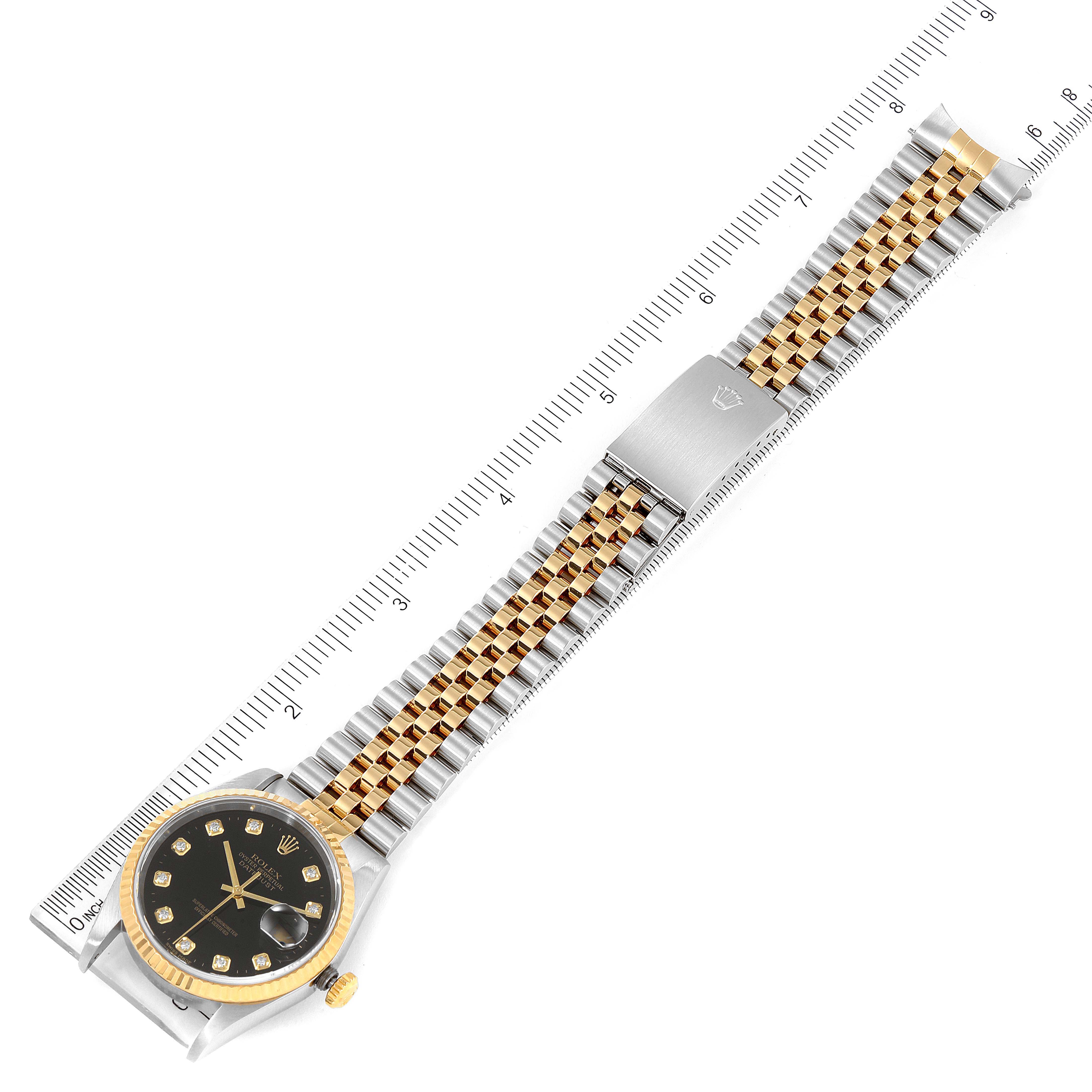The image shows the Rolex Datejust 16233 Men's Steel and Gold (two tone) Black Dial 16233 Men's Steel and Gold (two tone) Black Dial watch placed diagonally, highlighting the face, bezel, and two-tone bracelet against a ruler for scale.