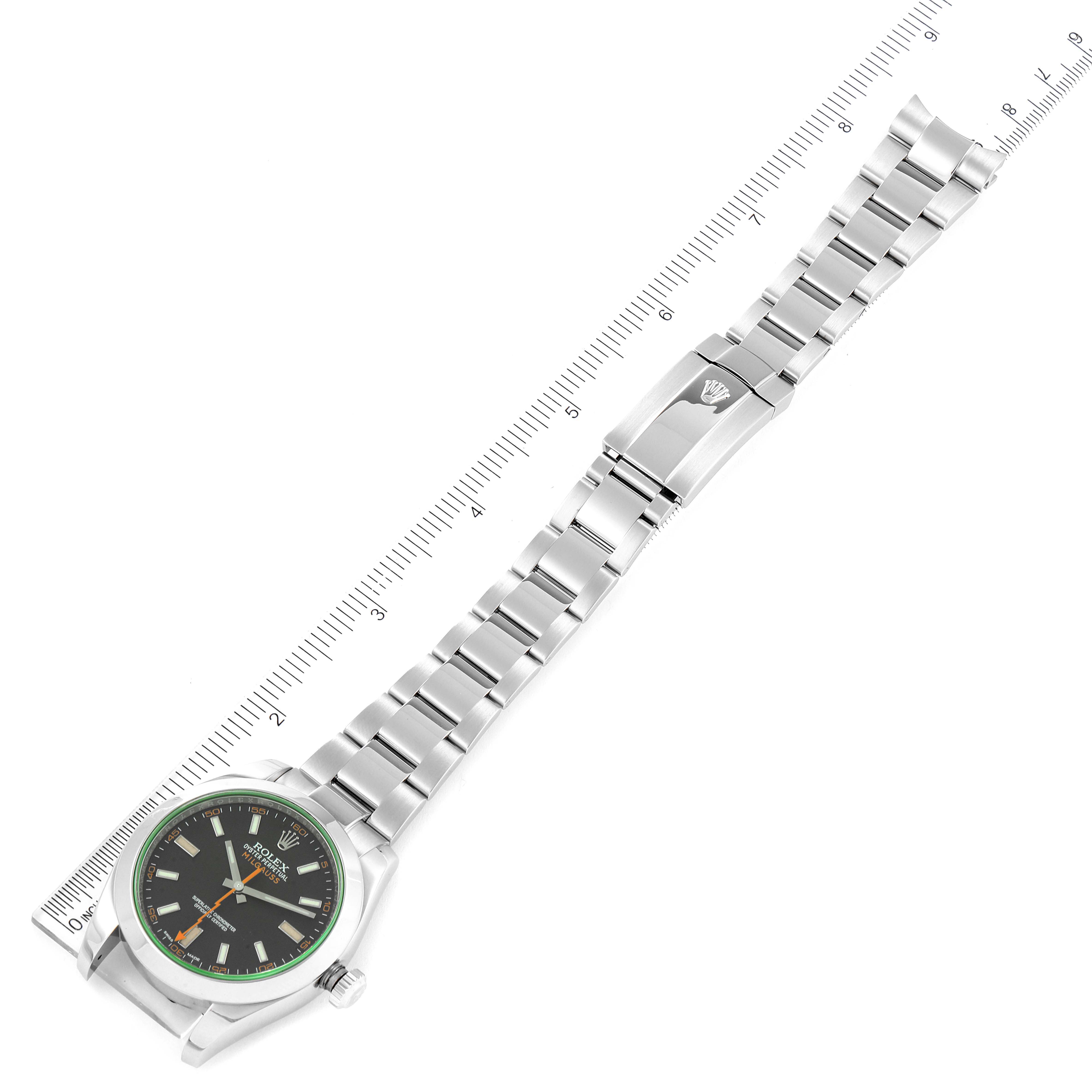 The Rolex Milgauss 116400V Men's Stainless Steel Black Dial 116400V Men's Stainless Steel Black Dial watch is shown from an aerial view, displaying its face, bracelet, and clasp against a ruler for scale.