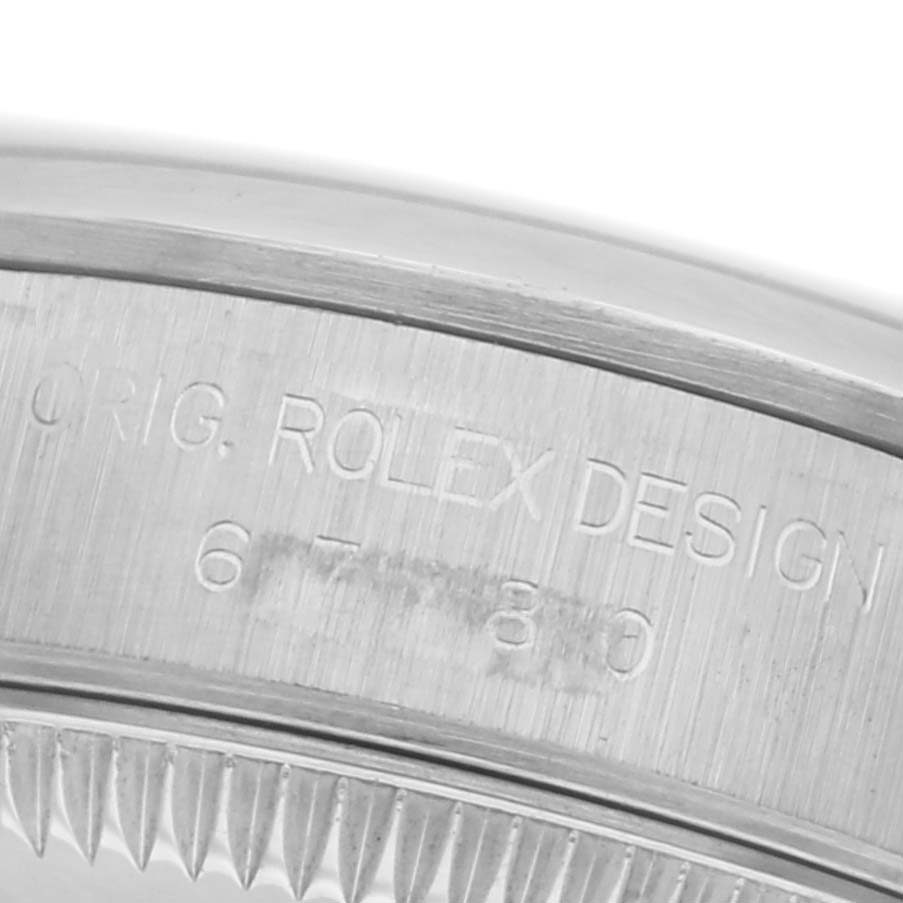 The image shows a close-up of the side of a Rolex Oyster Perpetual 67180 Women's Stainless Steel Black Dial 67180 Women's Stainless Steel Black Dial, highlighting the engraved text and fluted bezel edge.