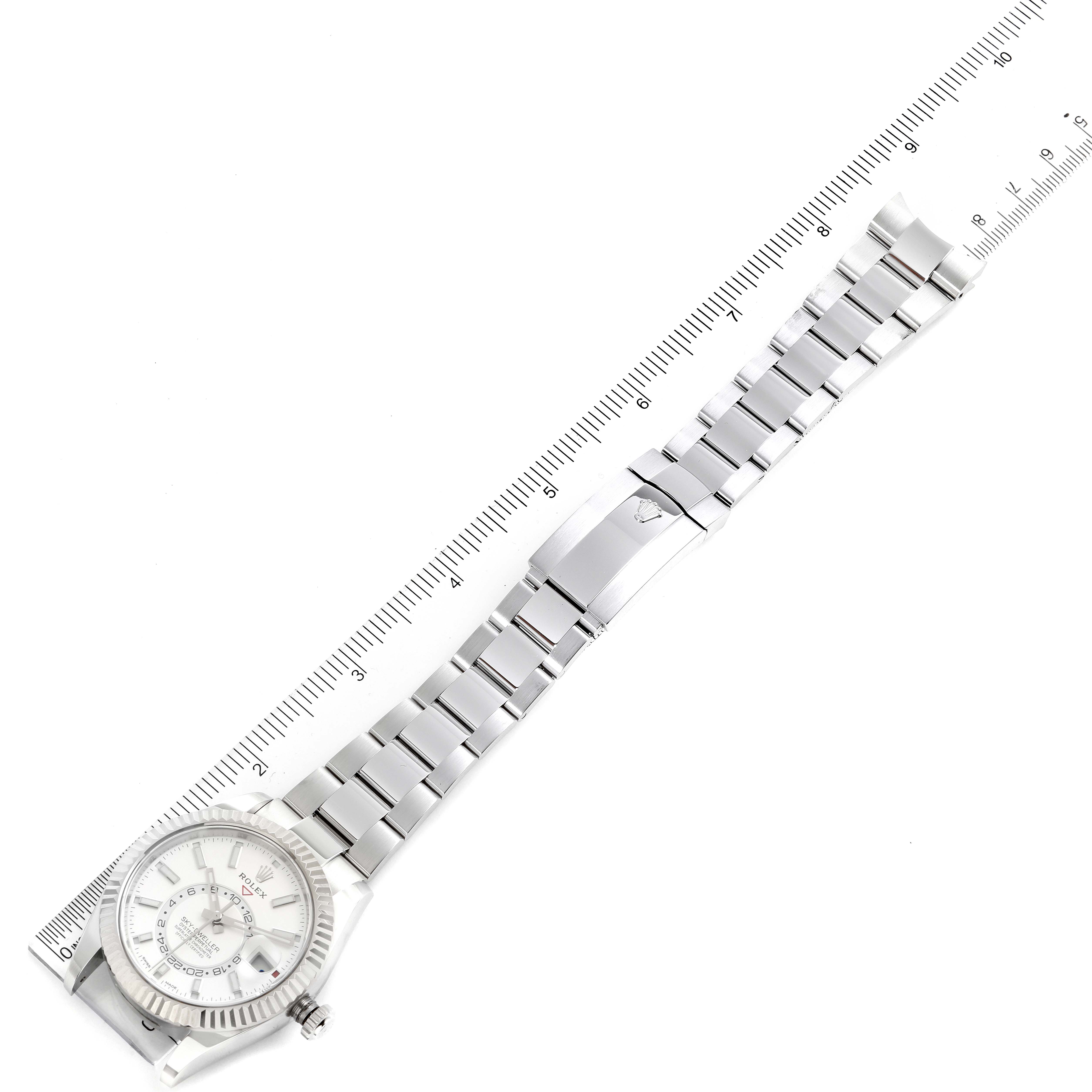This image shows a full view from above of the Rolex Sky-Dweller 326934 Men's Stainless Steel White Dial 326934 Men's Stainless Steel White Dial watch, including its dial, bezel, and metal bracelet next to a ruler.