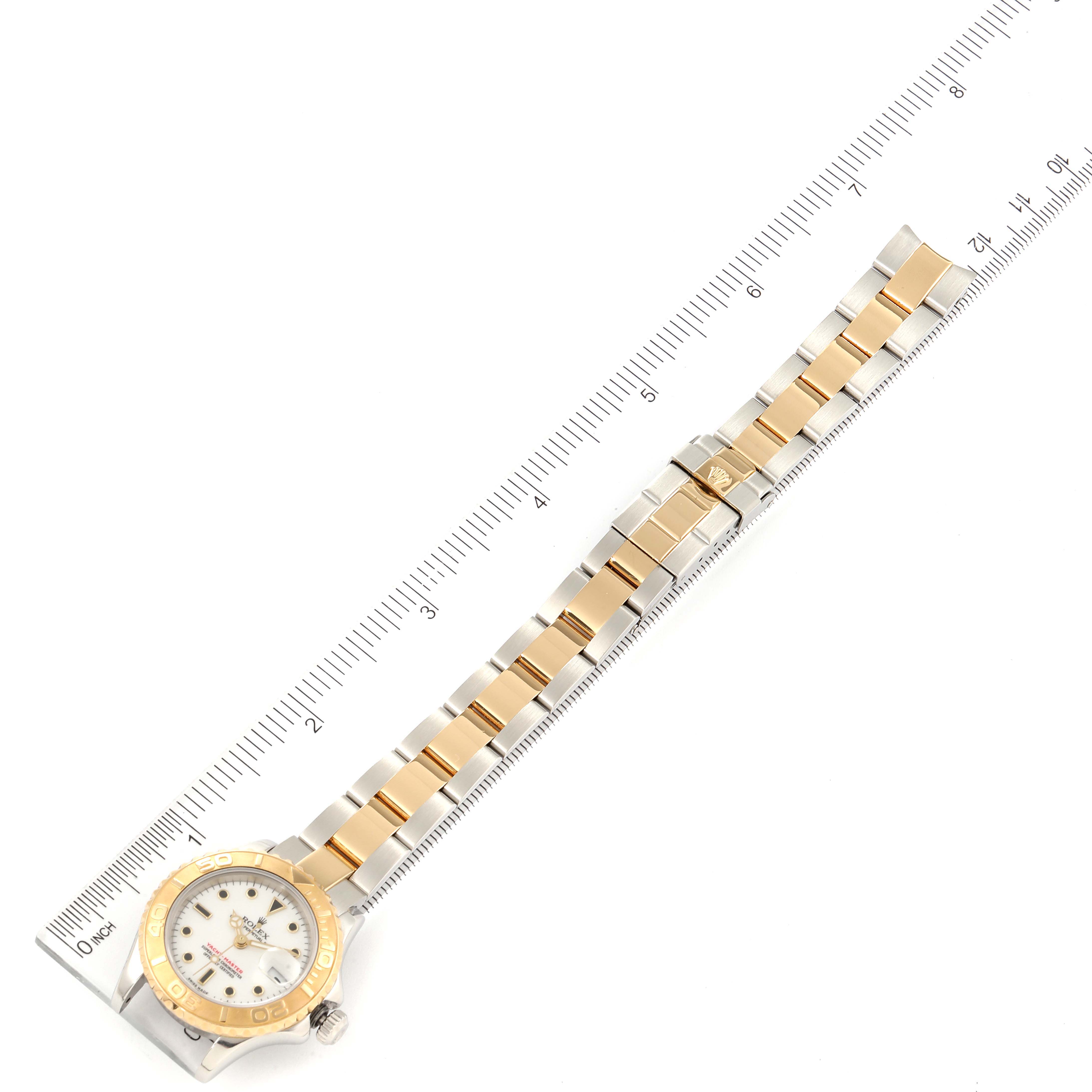 This image shows a top-down view of a Rolex Yacht-Master 169623 Women's Steel and Gold (two tone) White Dial 169623 Women's Steel and Gold (two tone) White Dial watch and its bracelet alongside a ruler for scale.