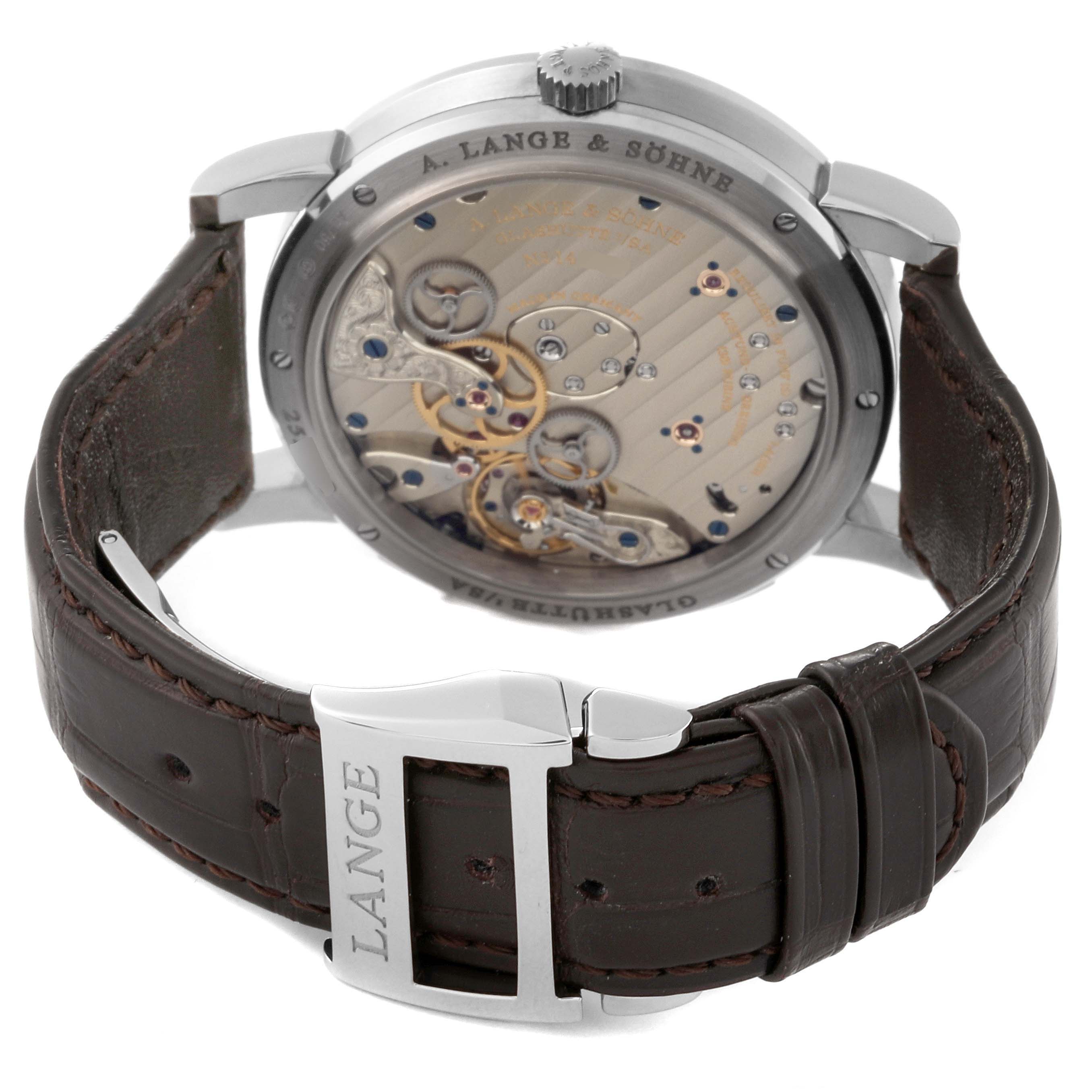 The image shows the back view of the A. Lange & Sohne Lange 1 136.029 Men's White Gold Black Dial watch, highlighting its intricate movement and leather strap with buckle.