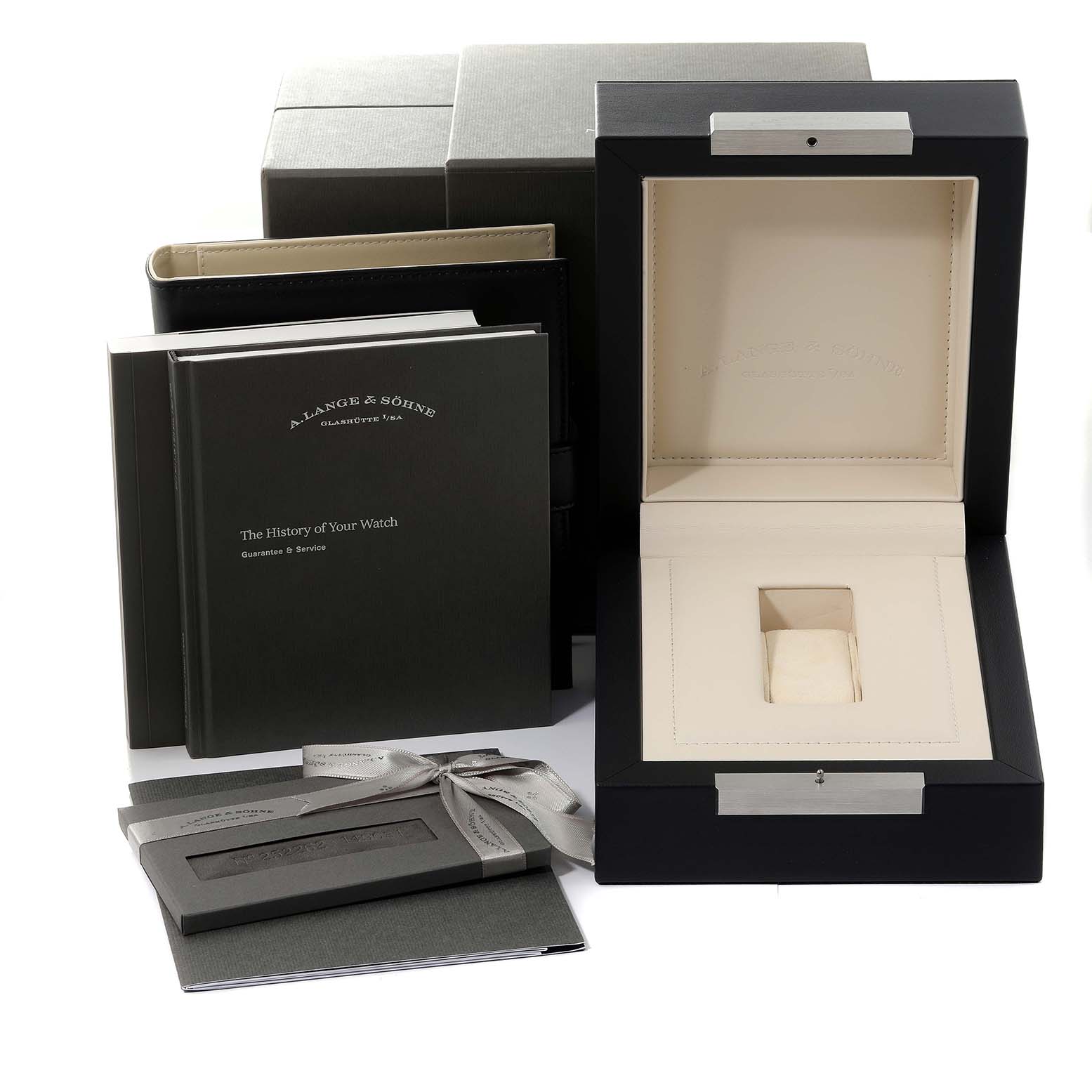 The image displays the accessories and packaging for the A. Lange & Sohne Lange 1 136.029 Men's White Gold Black Dial model, including a watch box, booklets, and documents.