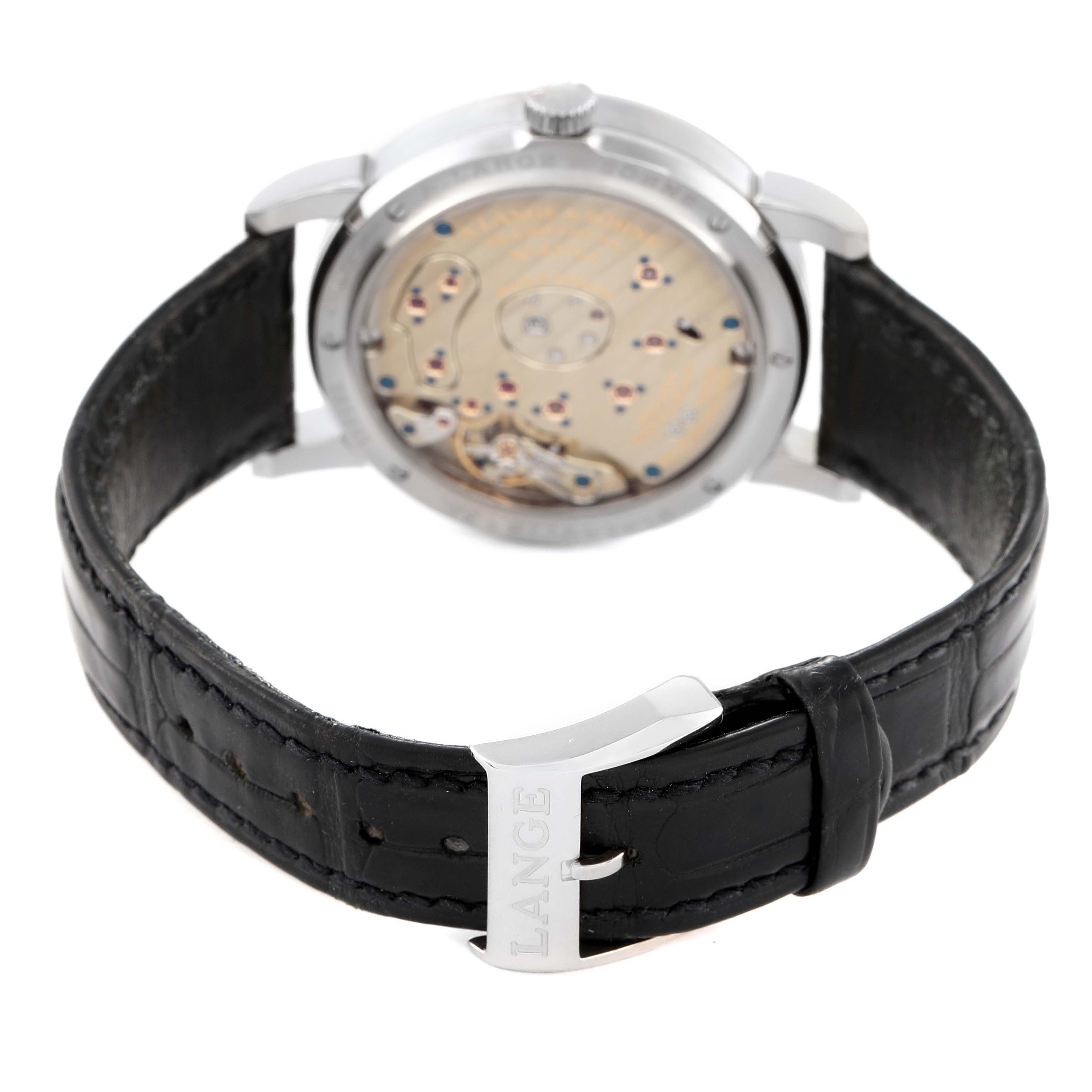 The image shows the back view of the A. Lange & Sohne Lange 1 191.039 Men's White Gold Silver Dial watch, highlighting its movement and black leather strap with the "LANGE" branded clasp.