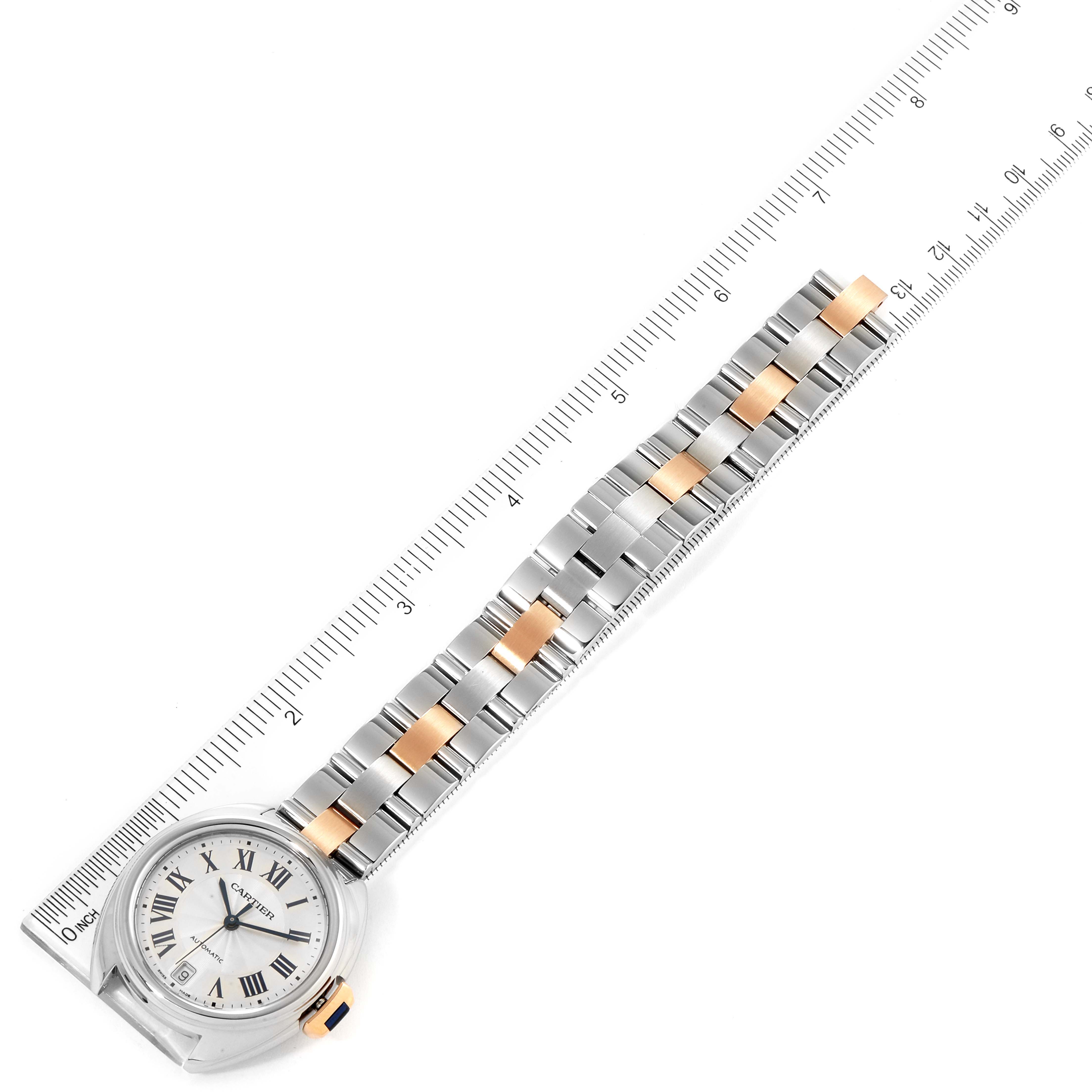This image shows an aerial view of a Cartier Cle W2CL0003 Women
s Steel and Gold (two tone) Silver Dial W2CL0003 Women
s Steel and Gold (two tone) Silver Dial watch laid next to a ruler, emphasizing the watch face and bracelet.