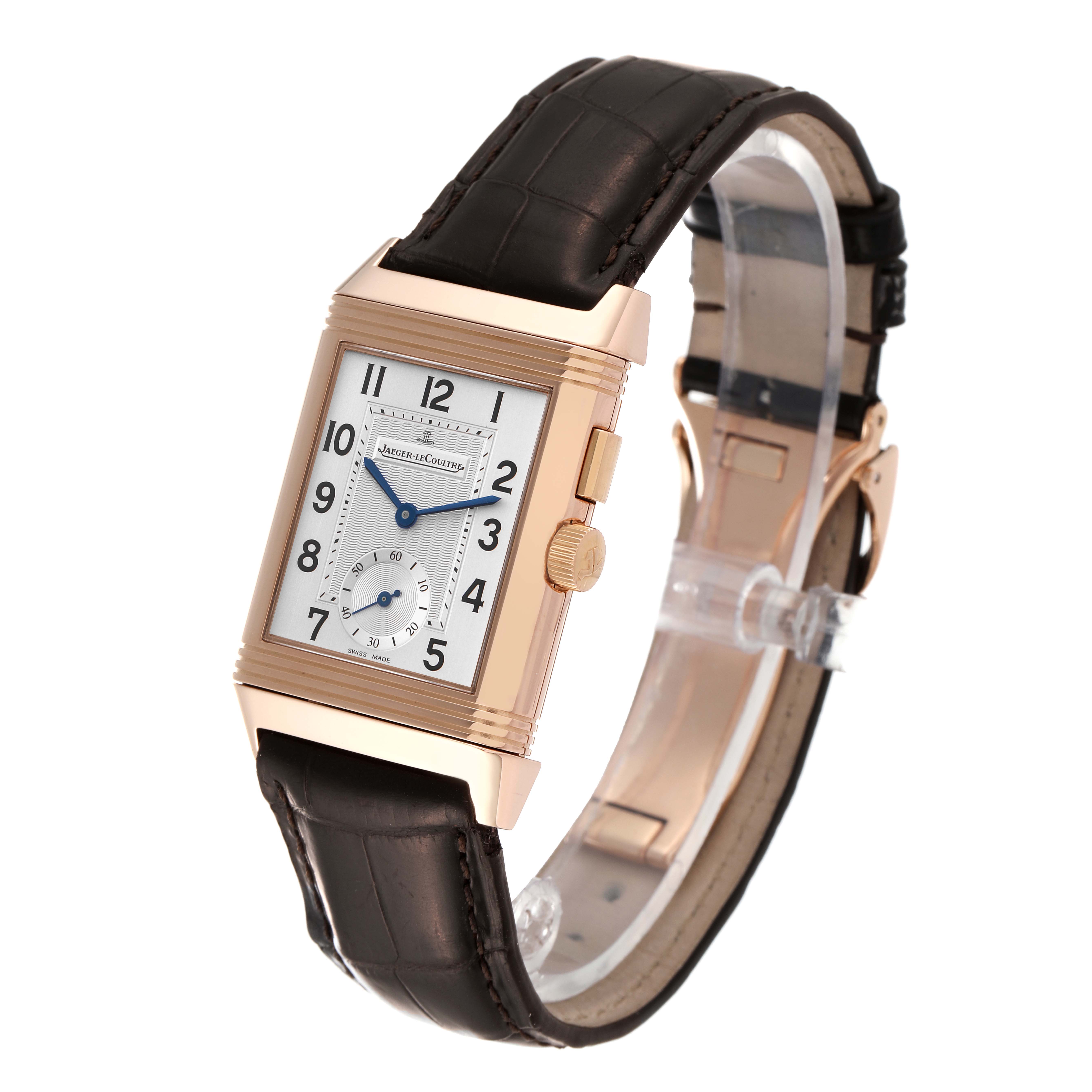 The Reverso model by Jaeger LeCoultre is shown from a three-quarter angle, displaying the dial, case, strap, and crown.