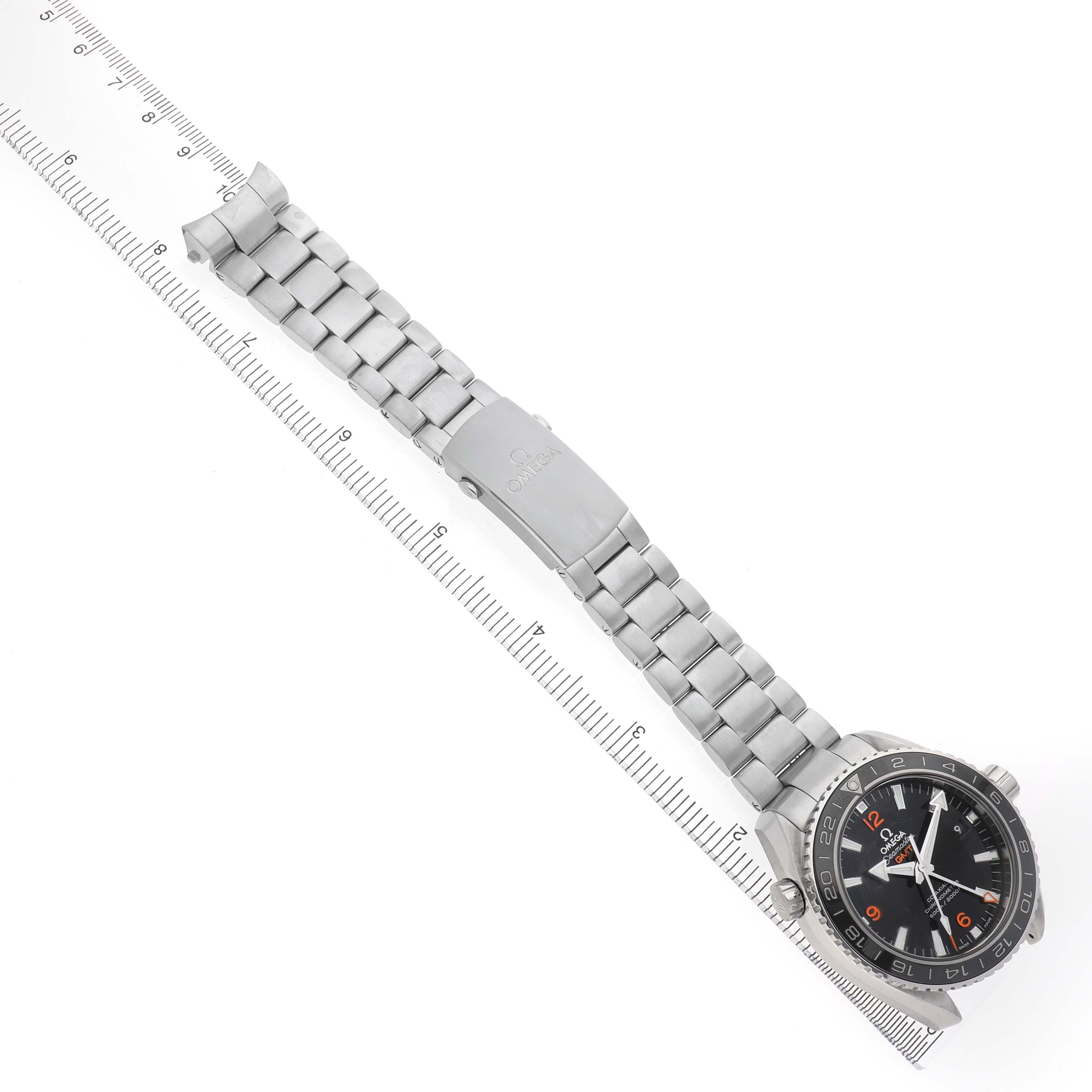 The Omega Planet Ocean 232.30.44.22.01.002 Men's Stainless Steel Black Dial watch is shown at a top angle, displaying its face, bezel, and full metal bracelet alongside a measuring ruler.